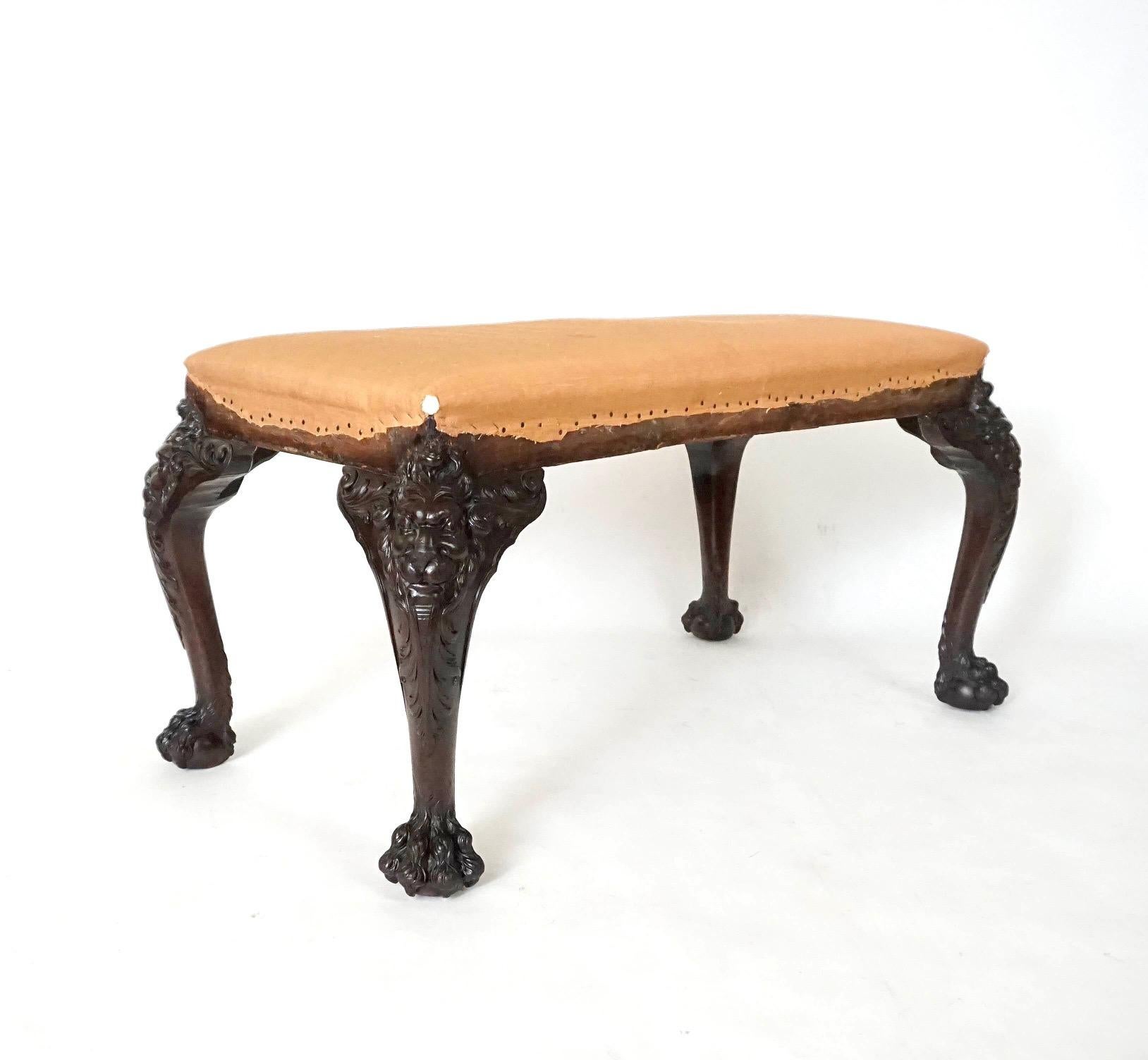 A circa 1890 English George II style long stool or bench commissioned by London dealer Henry Samuel having thickly carved cabriole legs in the manner of Daniel Bell and Thomas Moore with lion masks issuing acanthus leaves on hairy-paw feet. It is