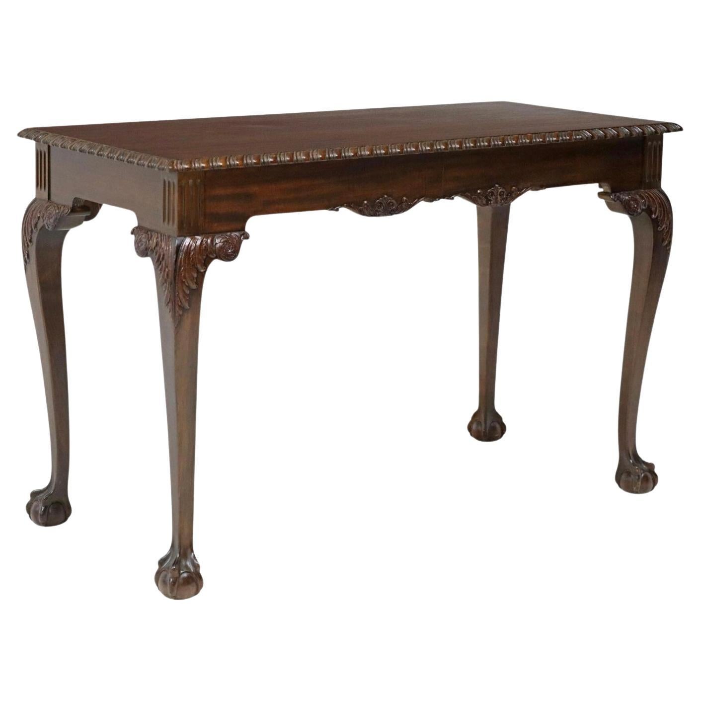 Mesa auxiliar o de biblioteca de caoba tallada estilo Jorge II. Principios del siglo XX. Tapa rectangular con borde estriado, patas cabriolé rematadas en acanto, sobre patas de bola y garra. 