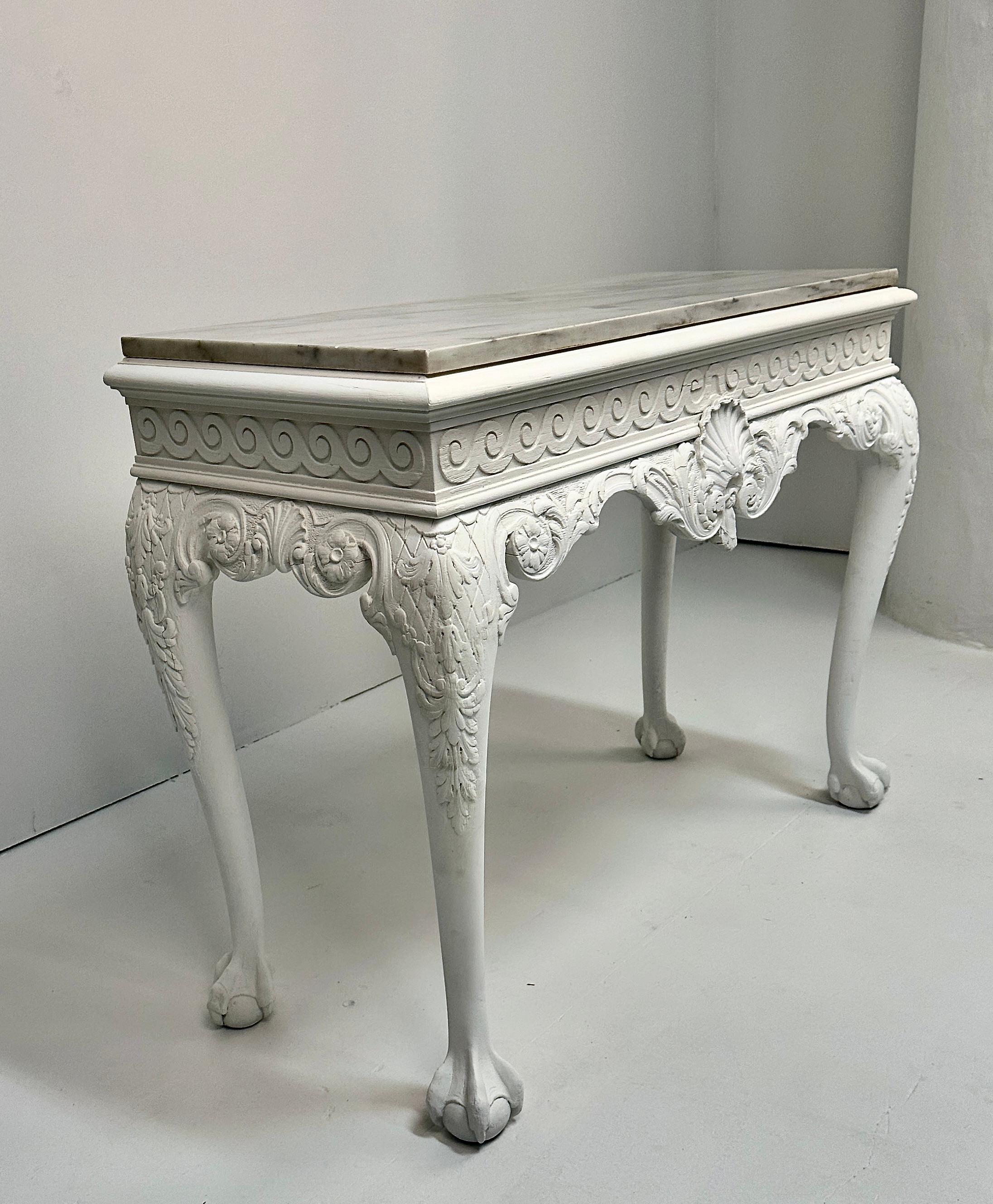 Handsome carved wood console, newly painted in a soft white, matte finish with original marble top.  Featuring classic Georgian center shell medallion  and carved wave frieze. The carved foliate cabriole legs end in ball an claw feet. Very fine