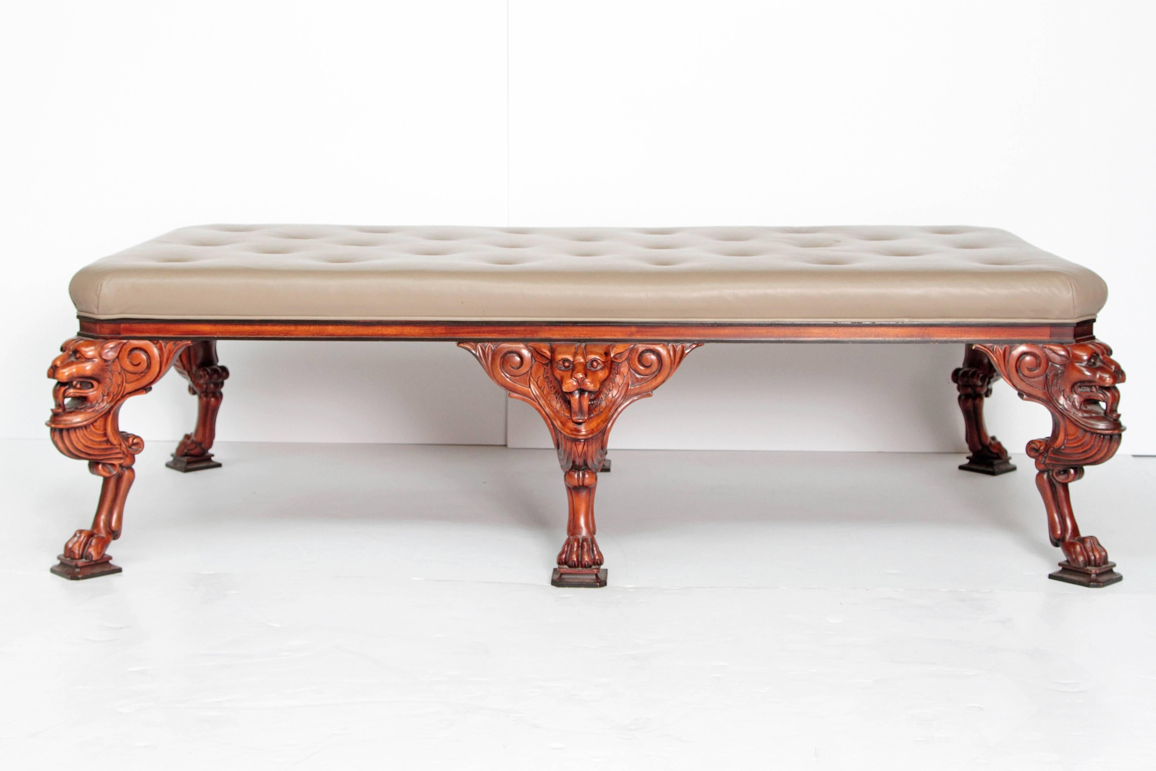 A vintage large George II-style upholstered leather button tufted bench / coffee table by Baker Furniture, highly decorative well carved lions heads at top of legs and paw feet at bottom.