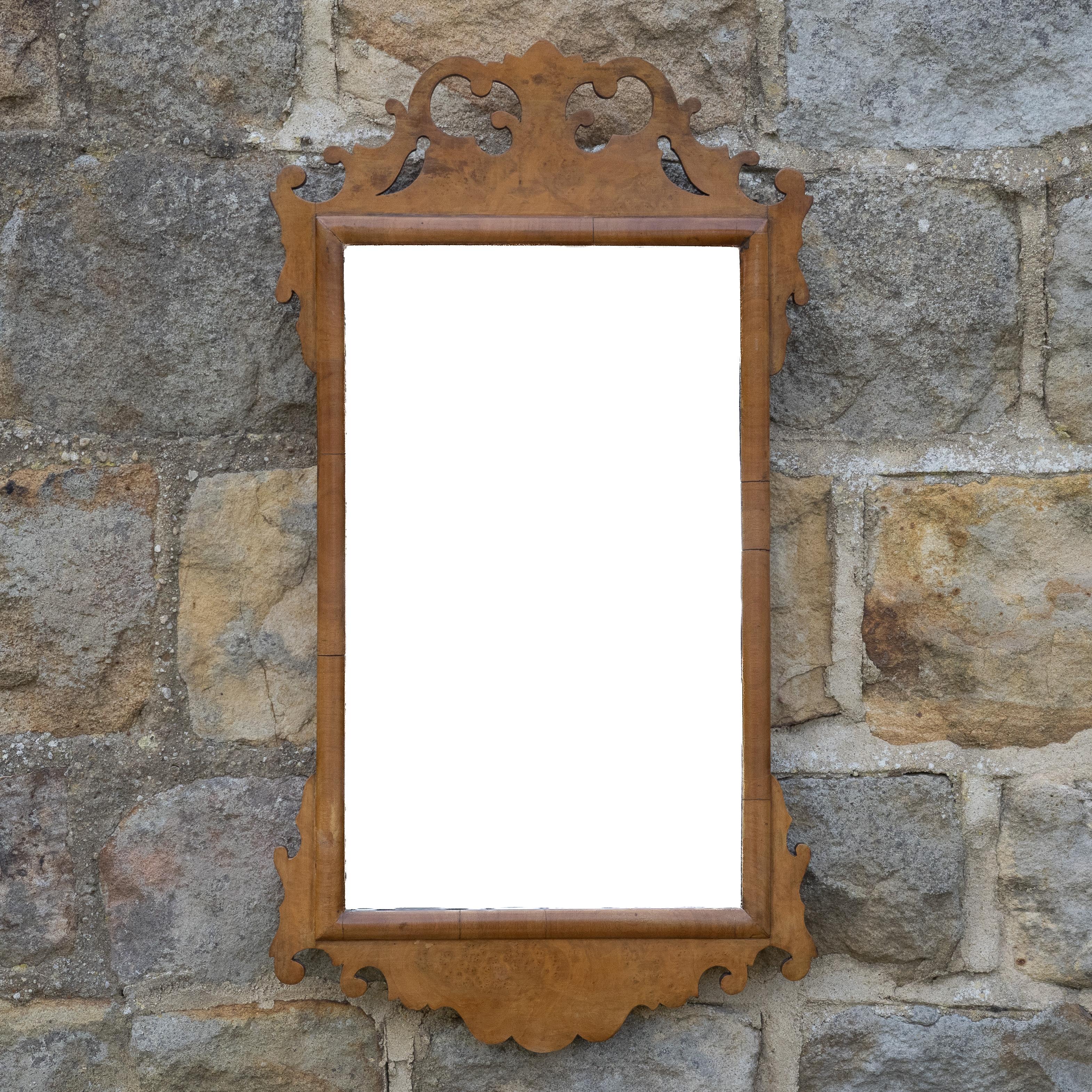 A George II style, burr walnut fretwork wall mirror, dating from the late 19th century, Victorian period.  This small wall mirror with burr walnut veneered fretwork frame, an oblong mirror plate with cushion moulded inner border. Wood panelled back