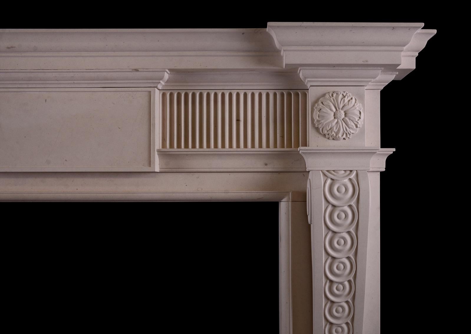 An elegant George II style fireplace in Lincoln limestone. The fluted frieze centred by plain panelled tablet, the acanthus leaf patera above bracketed jambs carved with guilloche decoration. Moulded breakfront shelf. English, a copy of a period