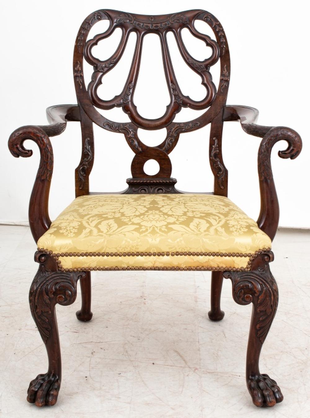This George II Style Mahogany Armchair, inspired by a design by Giles Grendey, is a fine example of late 19th-century craftsmanship. With its gracefully carved mahogany frame, the chair features a pierced backrest with an elegant shell or fan motif,