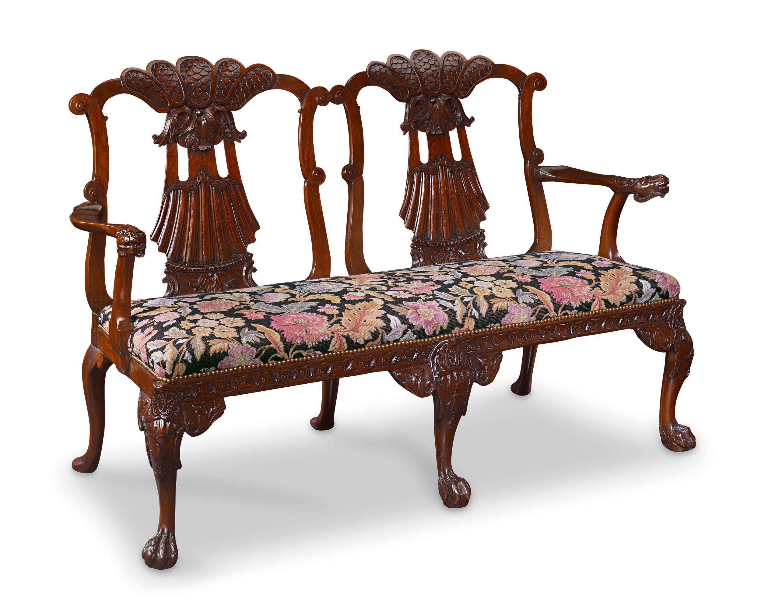 A magnificent mahogany double chair back settee crafted in the George II taste. From the scaled and scalloped back and zoomorphic armrests to the hairy ball-and-claw feet, the quality of the carving is deep and richly detailed. The seat is