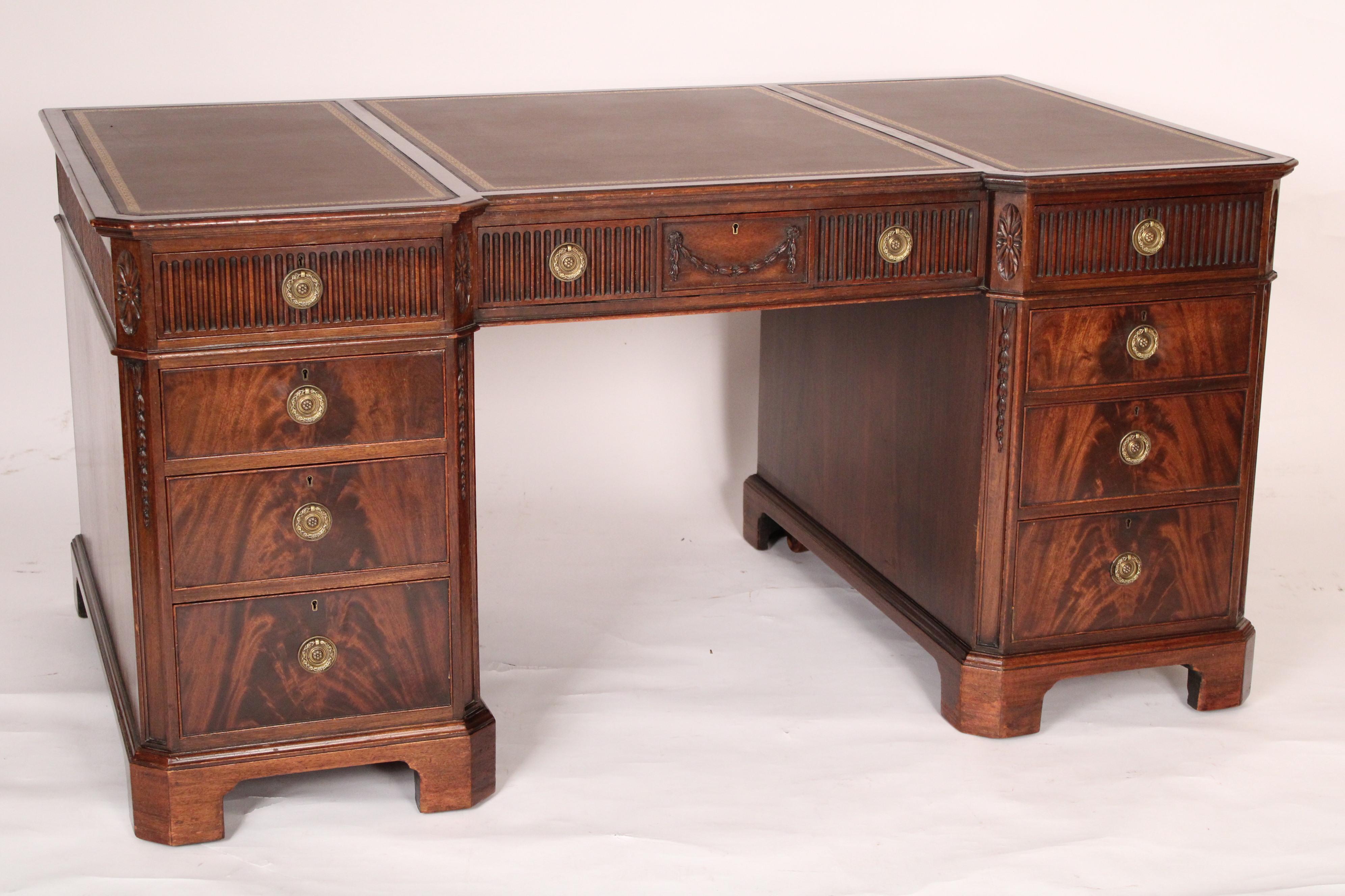 George II style mahogany double pedestal desk with a tooled leather top, circa 1910. The top with 3 sections of tooled leather, 3 frieze drawers the center frieze drawer with a carved swag, the 3 lower drawers on each side of knee hole with matched