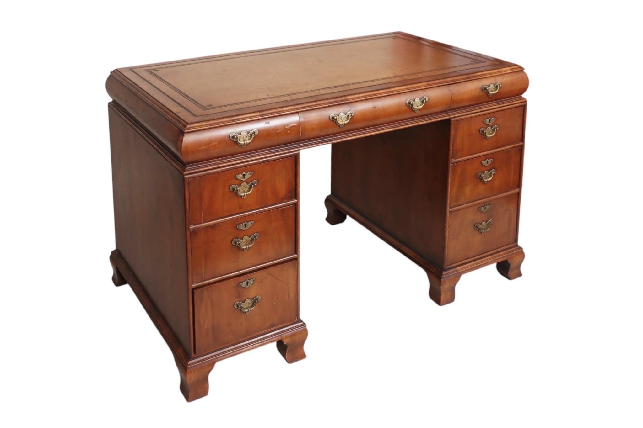 Scrittoio in mogano in stile Giorgio II con piano in pelle, circa 1920. L'area di scrittura in pelle marrone è decorata con una chiave greca lavorata e bordi con perline. Tre cassetti poco profondi sono alloggiati nel piano del tavolo sopra cinque