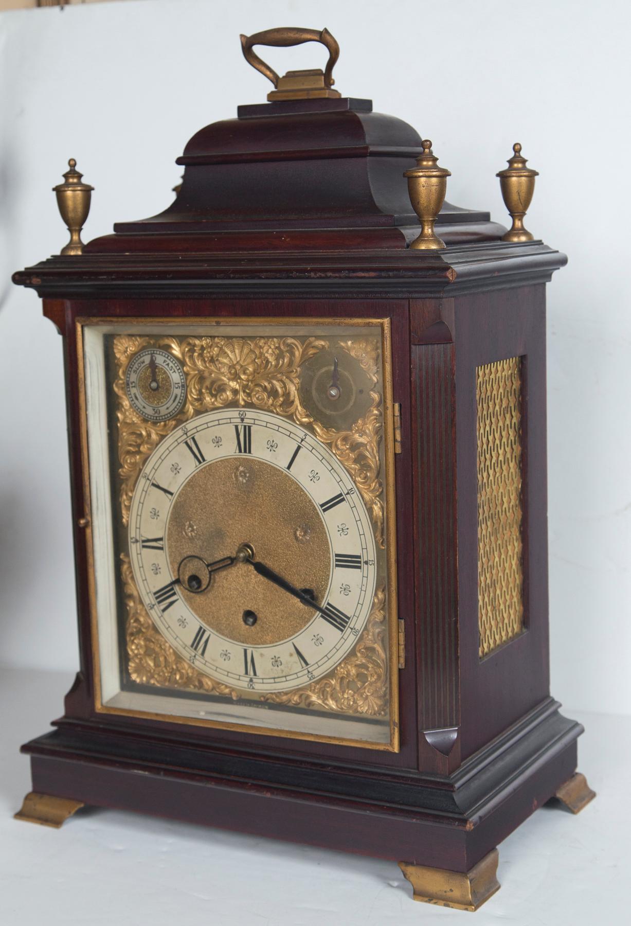 Made in Germany, in the English tradition and style. Brass bracket feet, finials, grill work on the sides and back, glass door frame. Brass handle 
 included in height. Six arms and rods strike the hours, half hours and Westminster (?) chime. Gilt