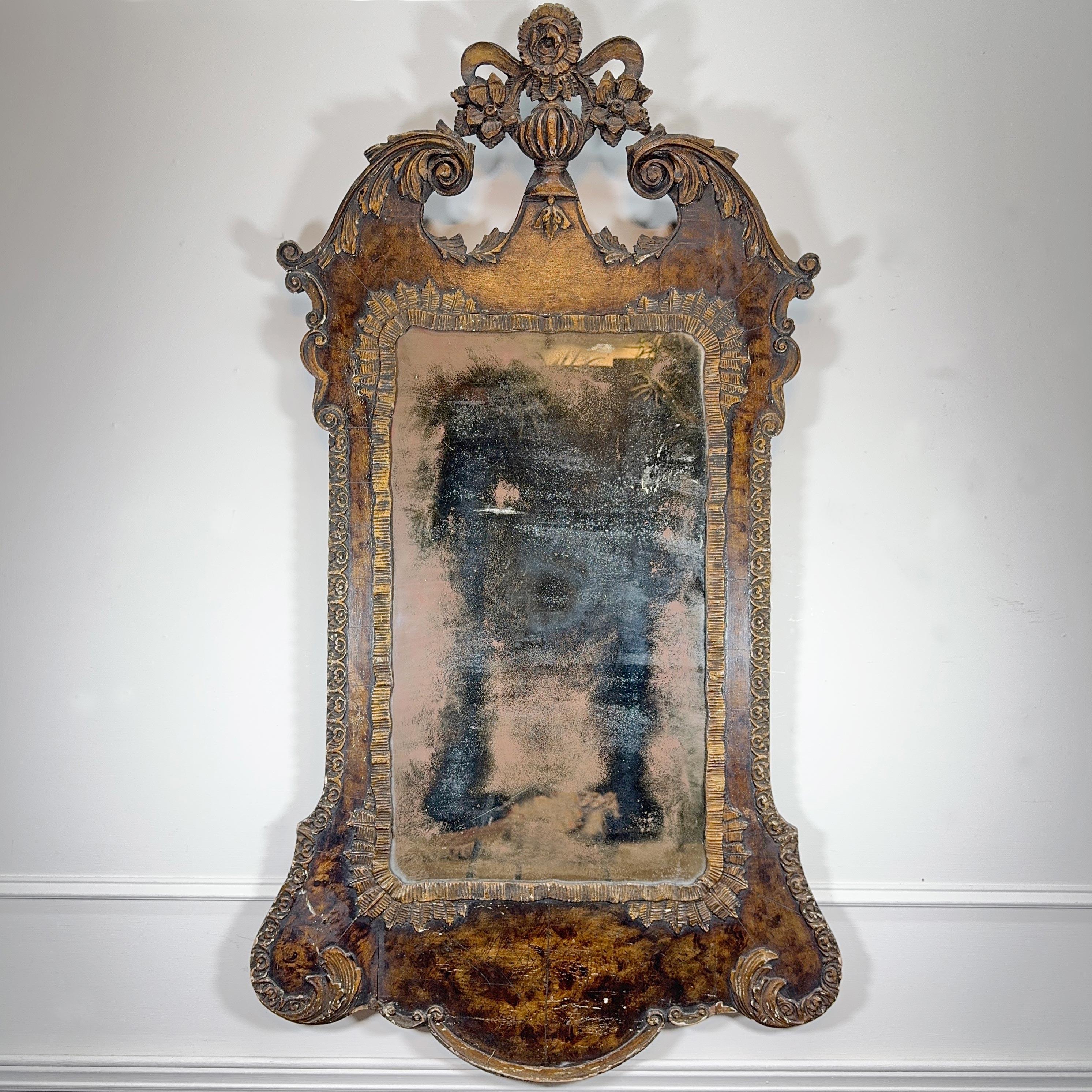 Un'impressionante specchiera da parete in stile George II della fine del XIX secolo, con cornice in noce intagliata a mano con elementi decorativi a volute e ornata da intagli dettagliati e delicati; la lastra e le spalliere originali sono ancora