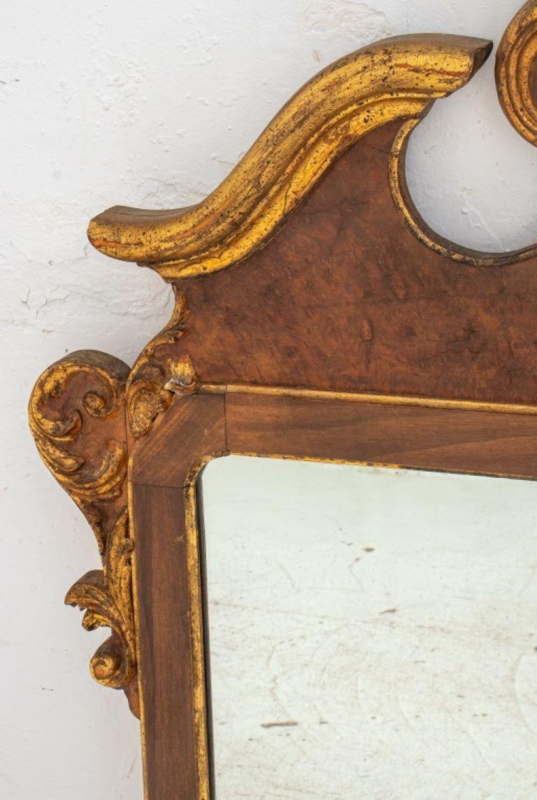 Miroir en bois de noyer doré de style George II, le rouleau sculpté surmonté d'un cartouche en forme, le tout flanqué d'un décor architectural et feuillu sculpté.

Dimensions : 49
