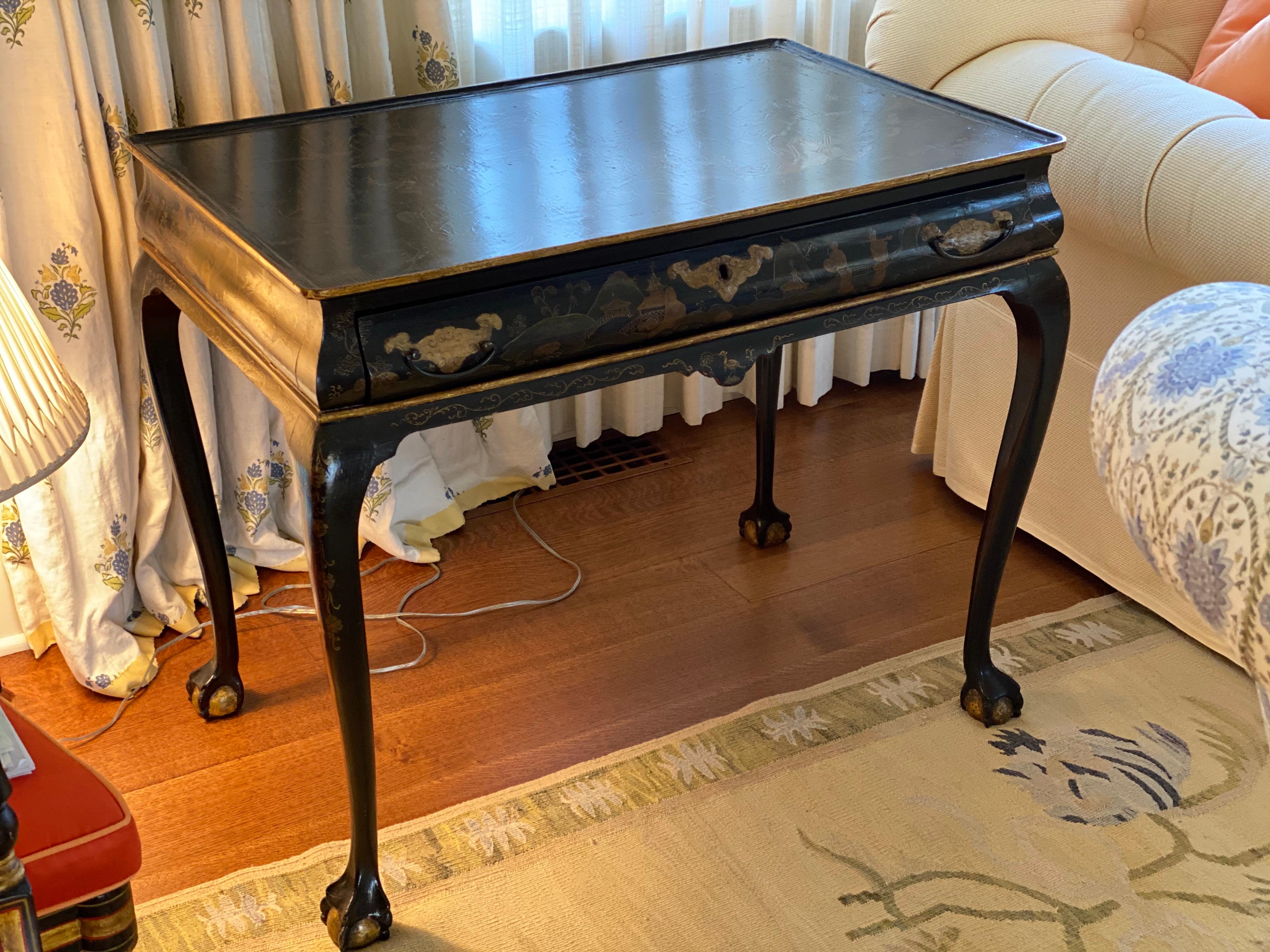 George II style parcel-gilt black japanned writing table, 19th century
Black and gold chinoiserie lacquer rectangular table with dished top above a conforming ogee-shaped frieze fitted with a drawer and raised on cabriole legs ending in claw and