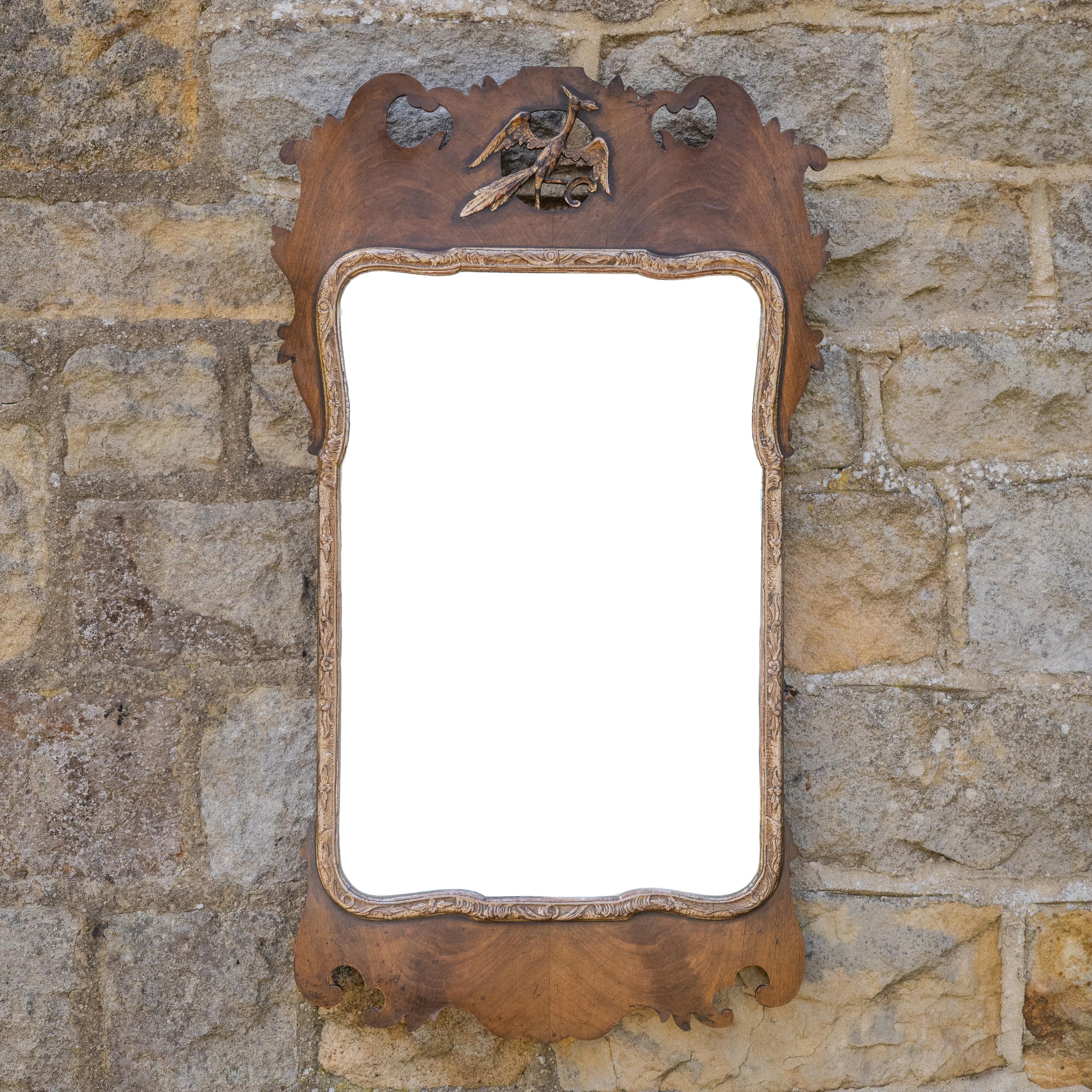 A George II style walnut and parcel gilt fretwork wall mirror, dating from the early 20th century, Edwardian period.  This wall mirror with book-matched walnut veneered fretwork frame, an oblong mirror plate with a parcel-gilt and gesso moulded