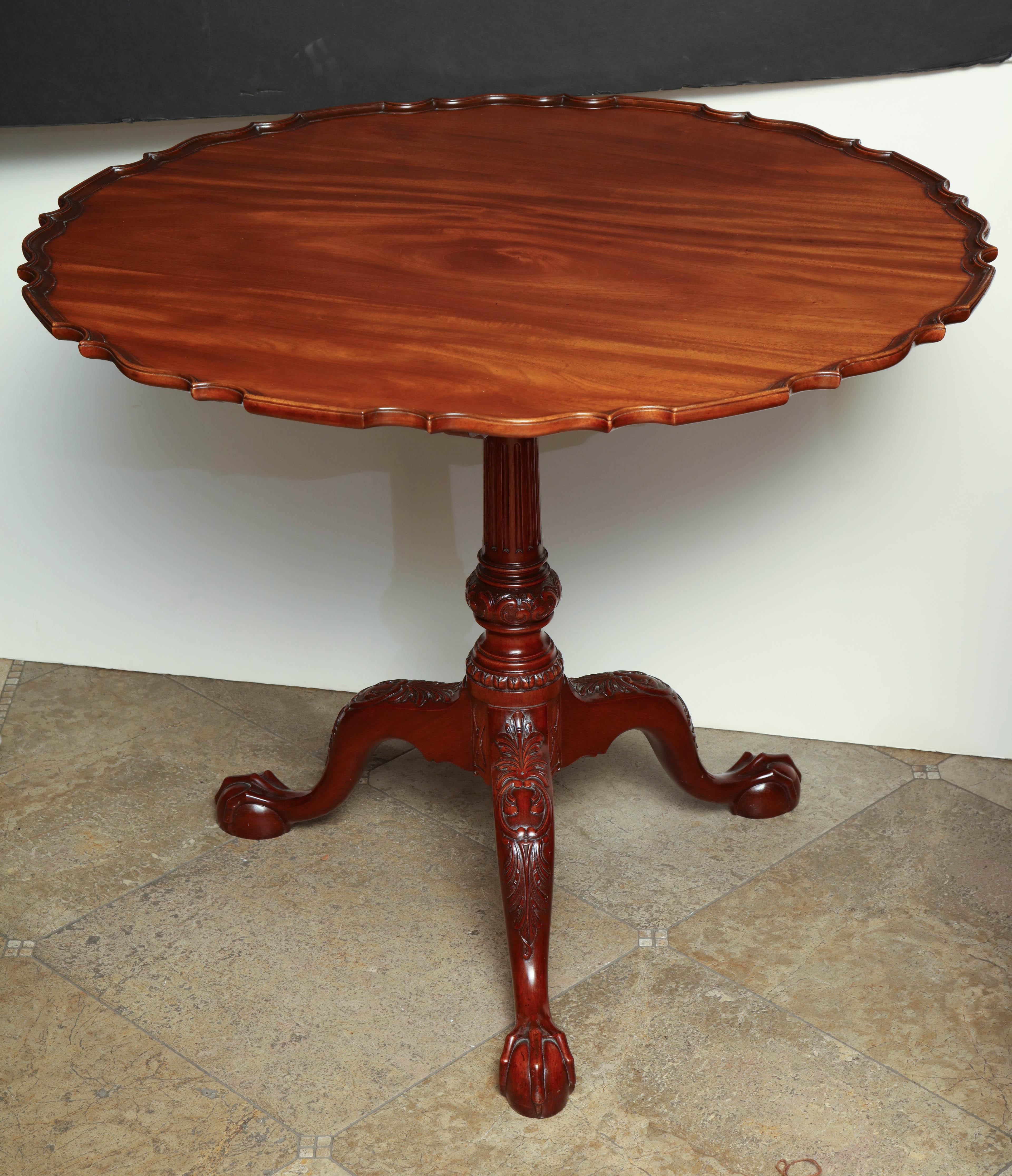 A large George II style carved mahogany pie crust tilt table with carved urn pedestal, carved cabriole legs on claw and ball feet.