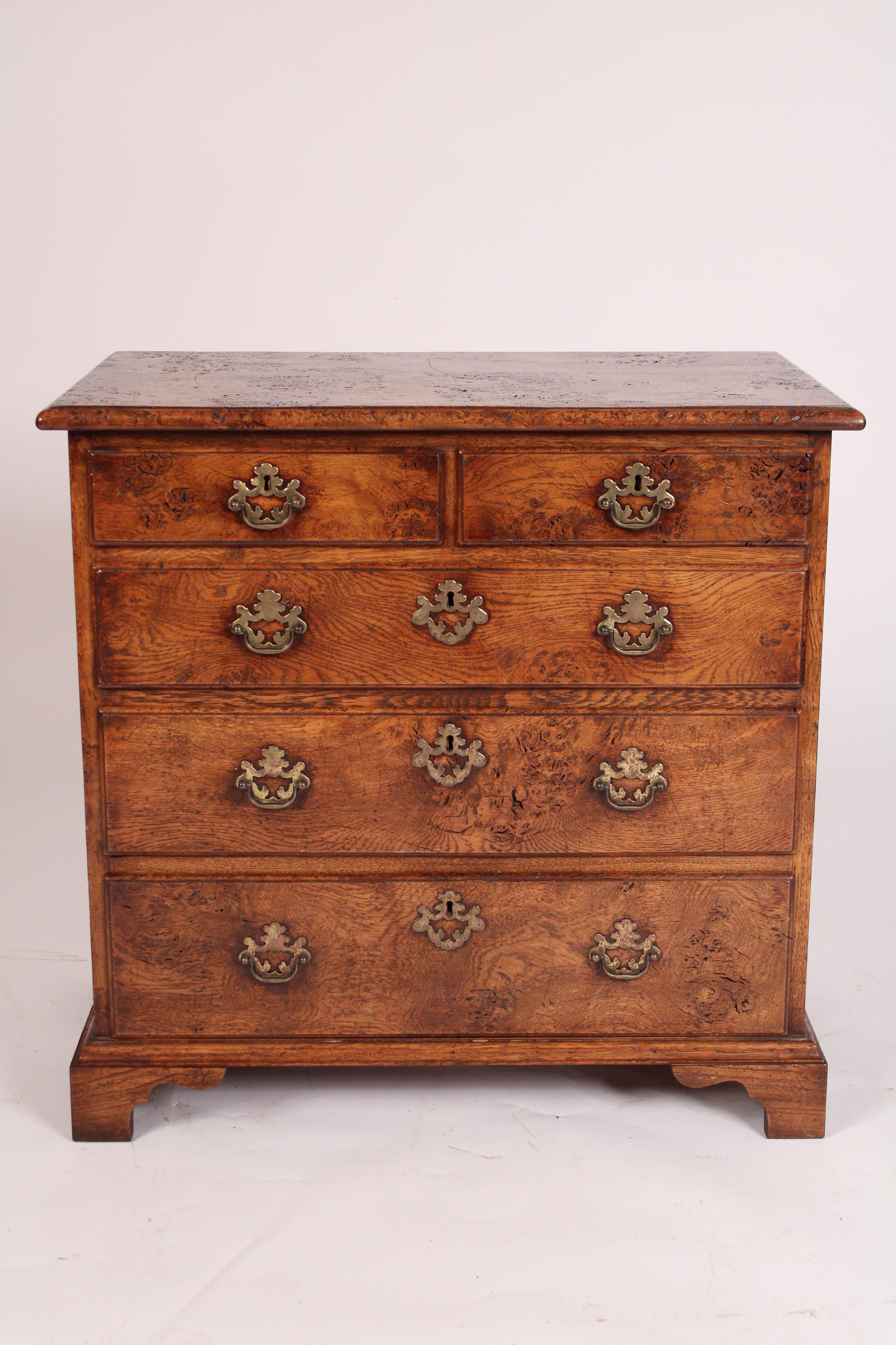 George II style pollard oak chest of drawers with brass hardware, circa 1950. With a single board top with molded front and side edges, two top drawers and three graduated lower drawers resting on bracket feet. Hand dove tailed drawer construction.