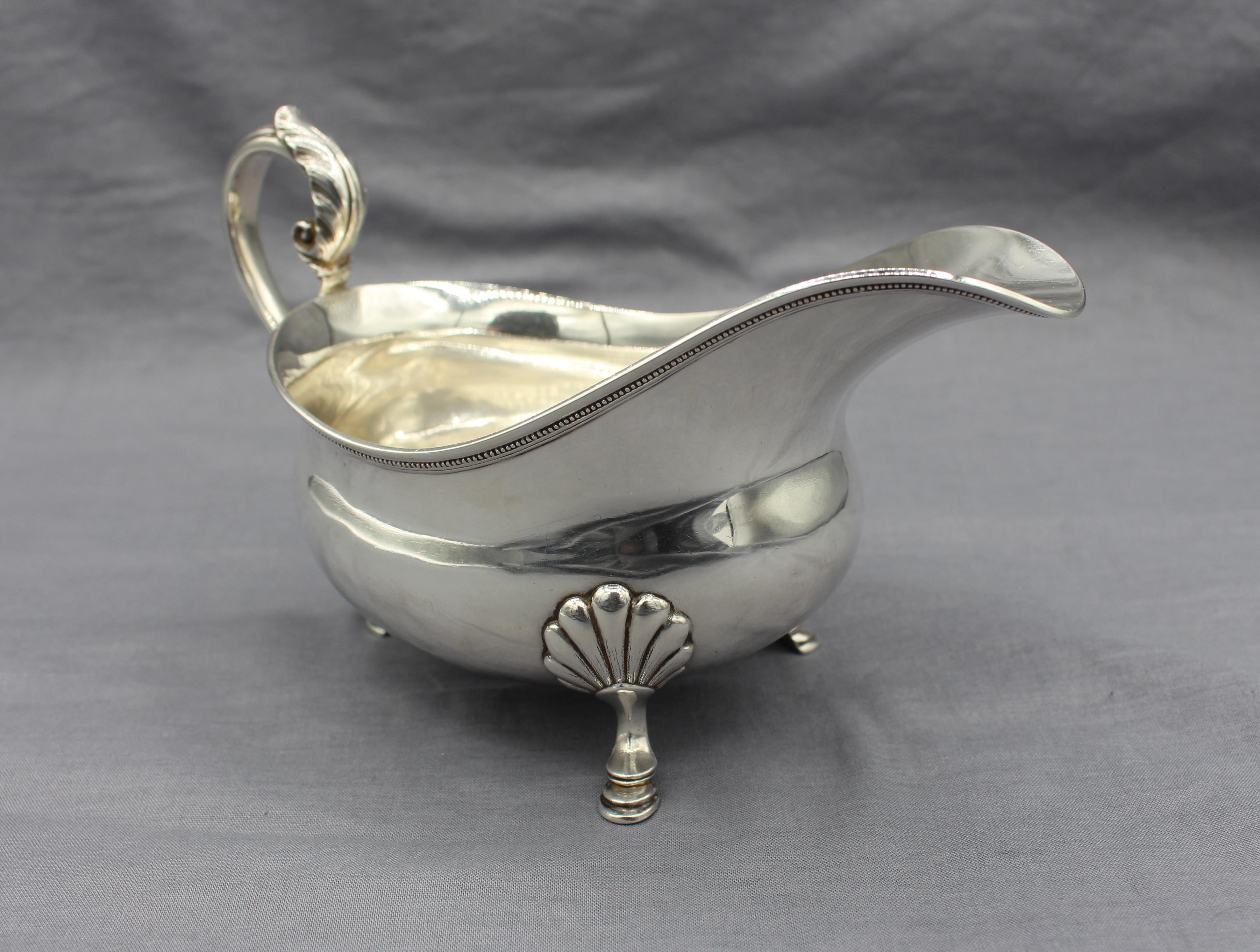 1907-1947 Tiffany sterling silver gravy boat. George II style, raised on hoof feet with shell knees & leaf mounted s-scroll handle. #4606/6281. Pattern of 1876. Made in the era of John C. Moore, 1907-1947. Some light denting. 7.60 troy oz. Measures: