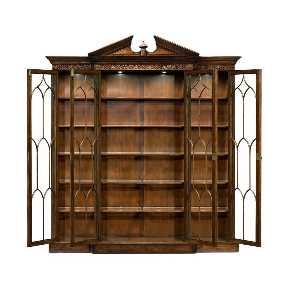 George II style walnut veneered and crossbanded china display cabinet, the central section with a broken pediment centered with an urn, the whole with glazed full-length doors with Gothic ogee topped glazing bars, adjustable glass inset shelves, and