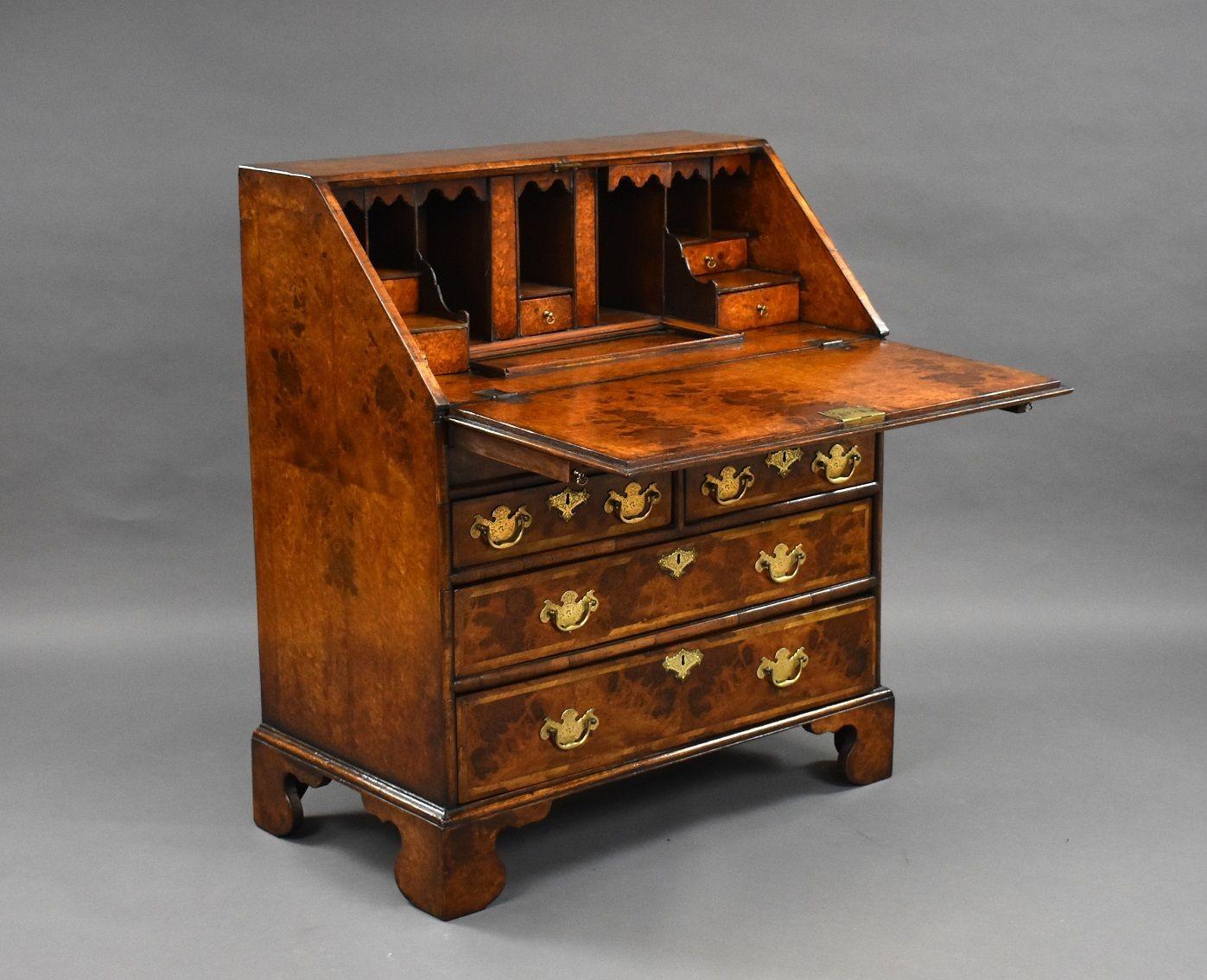 George II style walnut bureau with pull-down fall revealing pigeon holes and small drawers, also pull out bookends with a separate slide below for storage. Below the top it has two small drawers and two long drawers with brass handles stands on