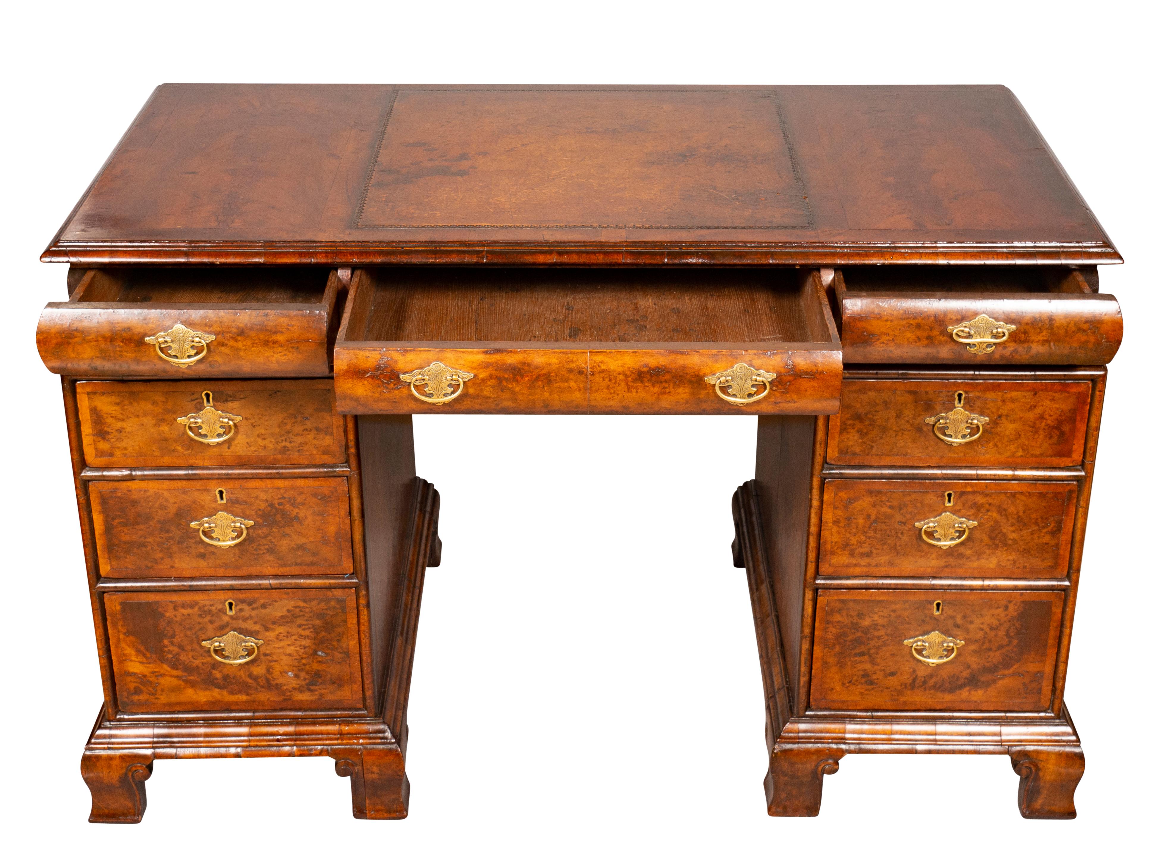 Rectangular top with inset brown leather over a cushion frieze with three drawers, the reverse finished but no drawers, pedestal base each containing three drawers. Bracket feet.