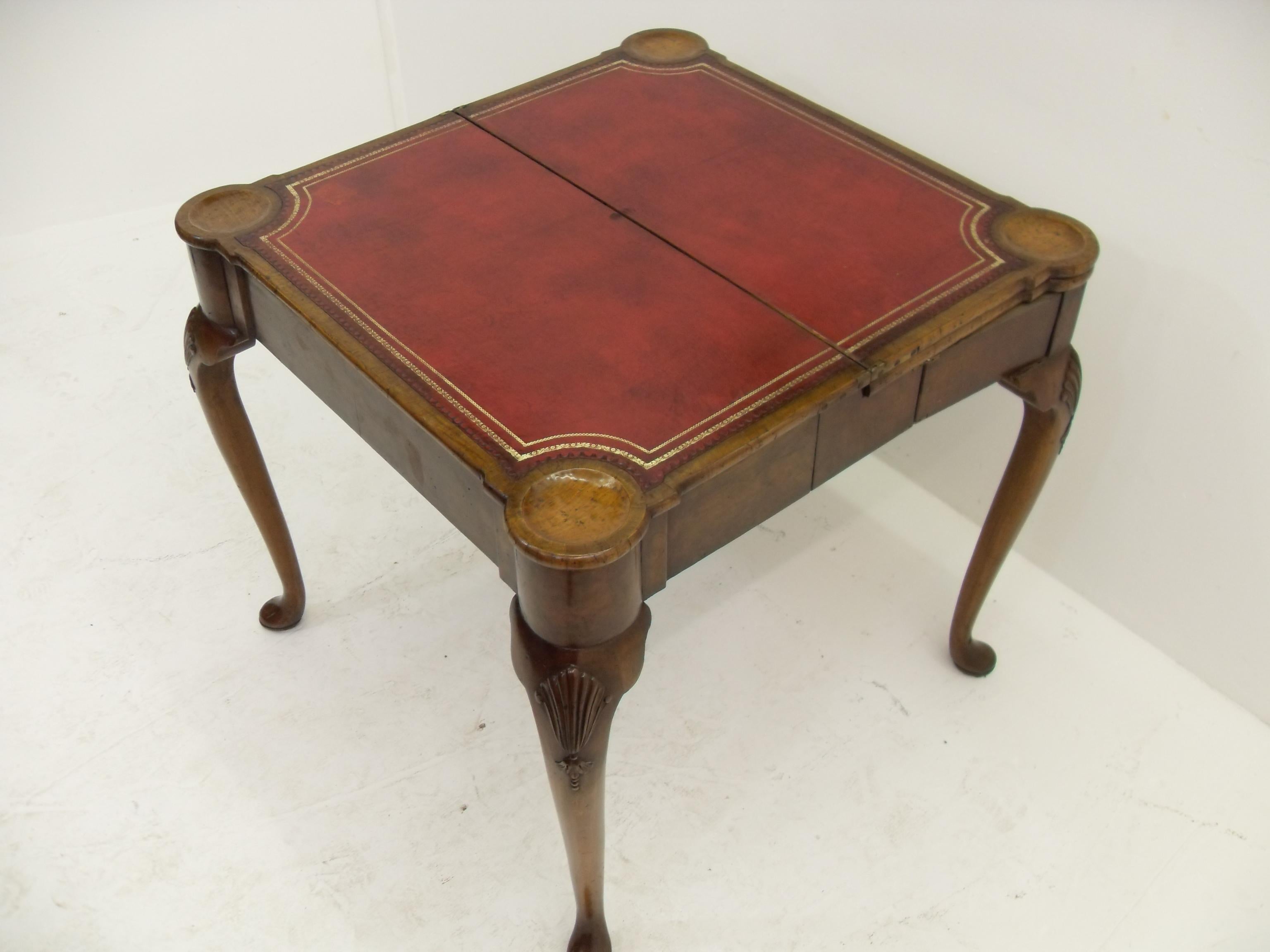A triple layer George II style mahogany card or tea table, with a concertina action to the legs. The top unfolding to reveal a tea table with polished walnut top, opening again to reveal a card table with carved guinea wells and a gilt leather