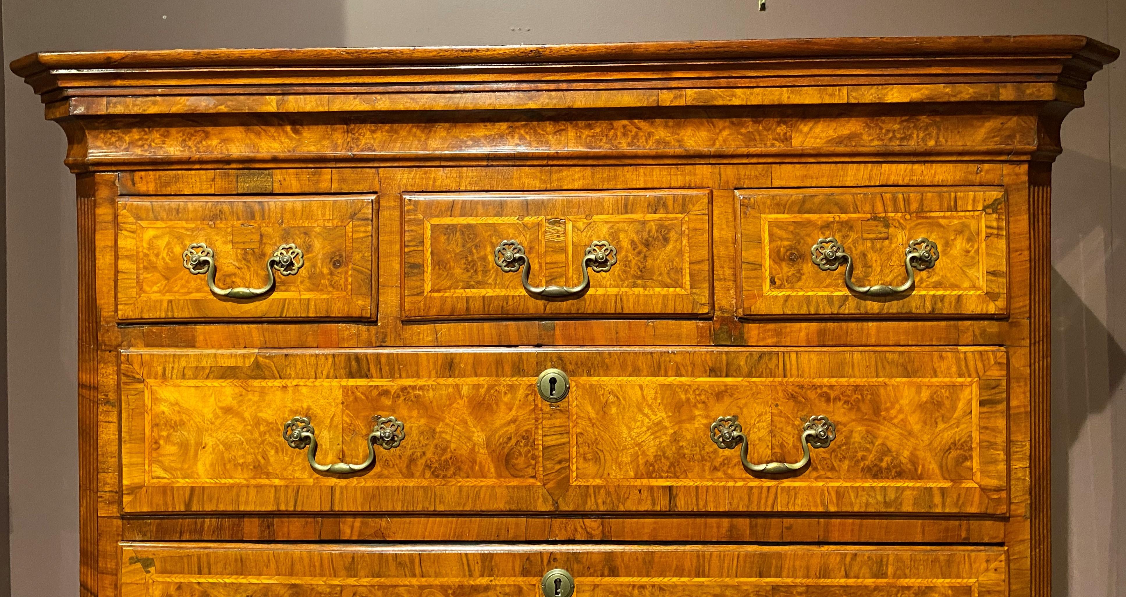 A fine English George II walnut and burled walnut veneered chest on chest, the upper case with a molded cornice surmounting three aligned and three graduated drawers, flanked by canted reeded corners, over a lower case with a mid-section dressing