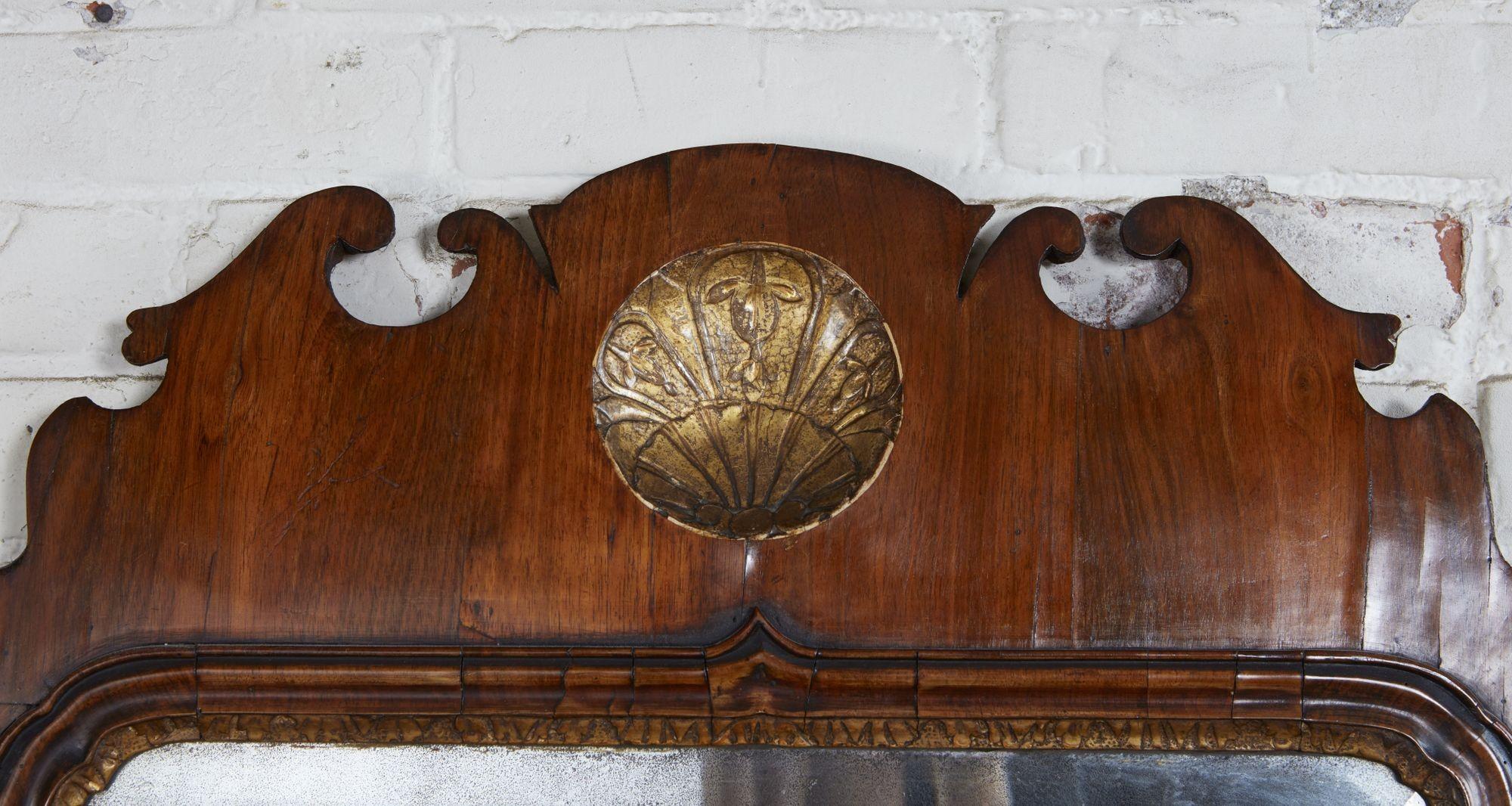 Very fine early Georgian walnut and parcel gilt mirror, the scalloped crest with inset carved gesso and gilt scallop shell over molded frame surrounding original shaped and beveled mercury glass plate, the walnut with good rich patination and the