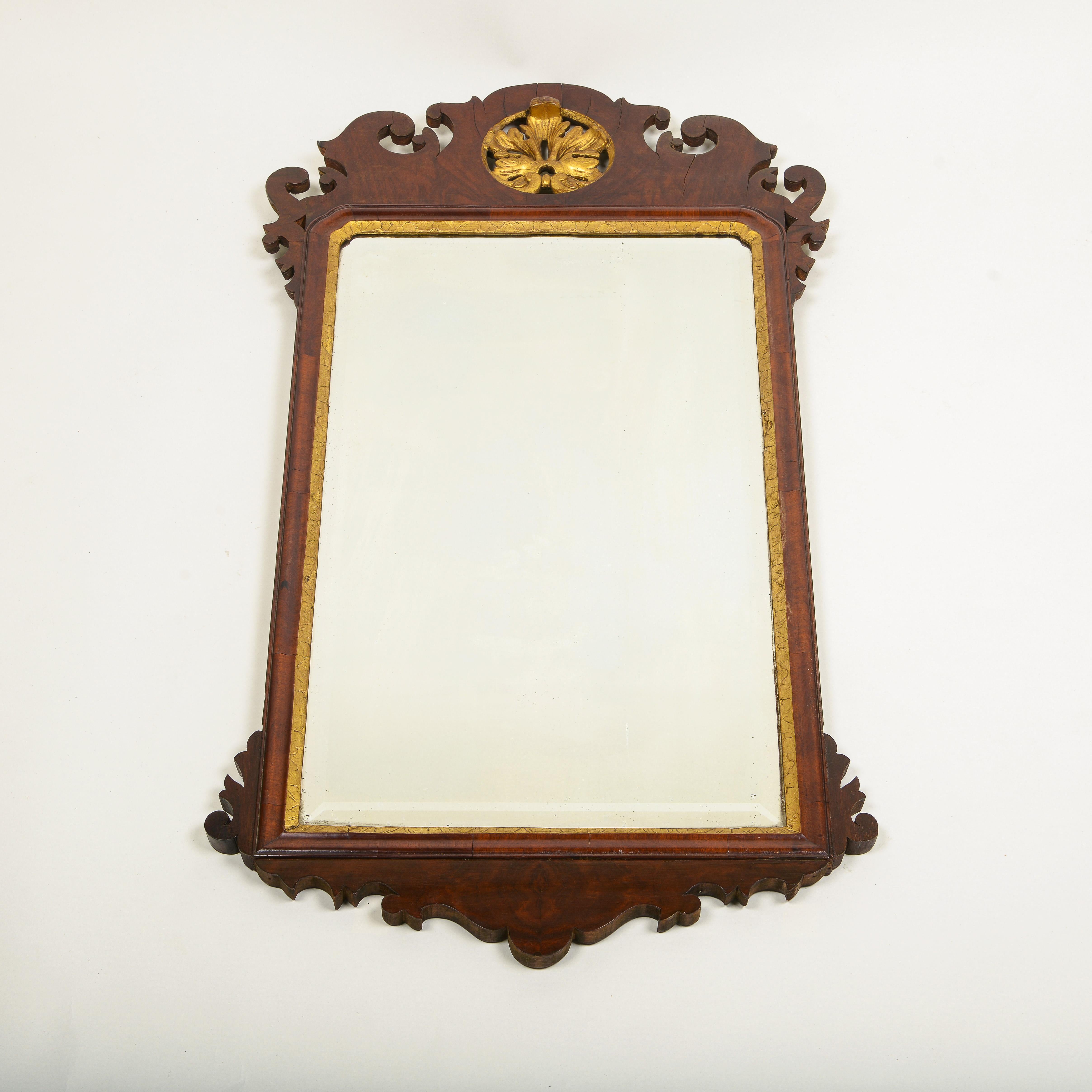 The rectangular beveled plate within a conforming surround with arched scrolling cresting, centered by a gilt foliate clasp, and apron.