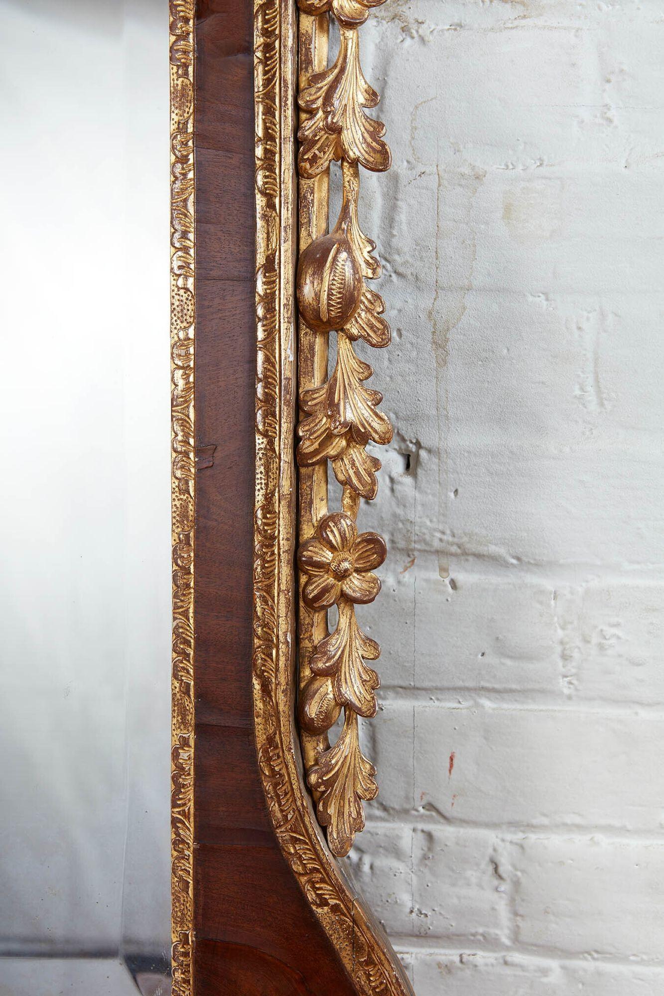 Very fine George II walnut and parcel gilt mirror, the phoenix bird finial surmounted by acanthus carved swan neck pediment, the foliate carved and water gilt moldings beautifully burnished and retaining original beveled mercury glass plate, the
