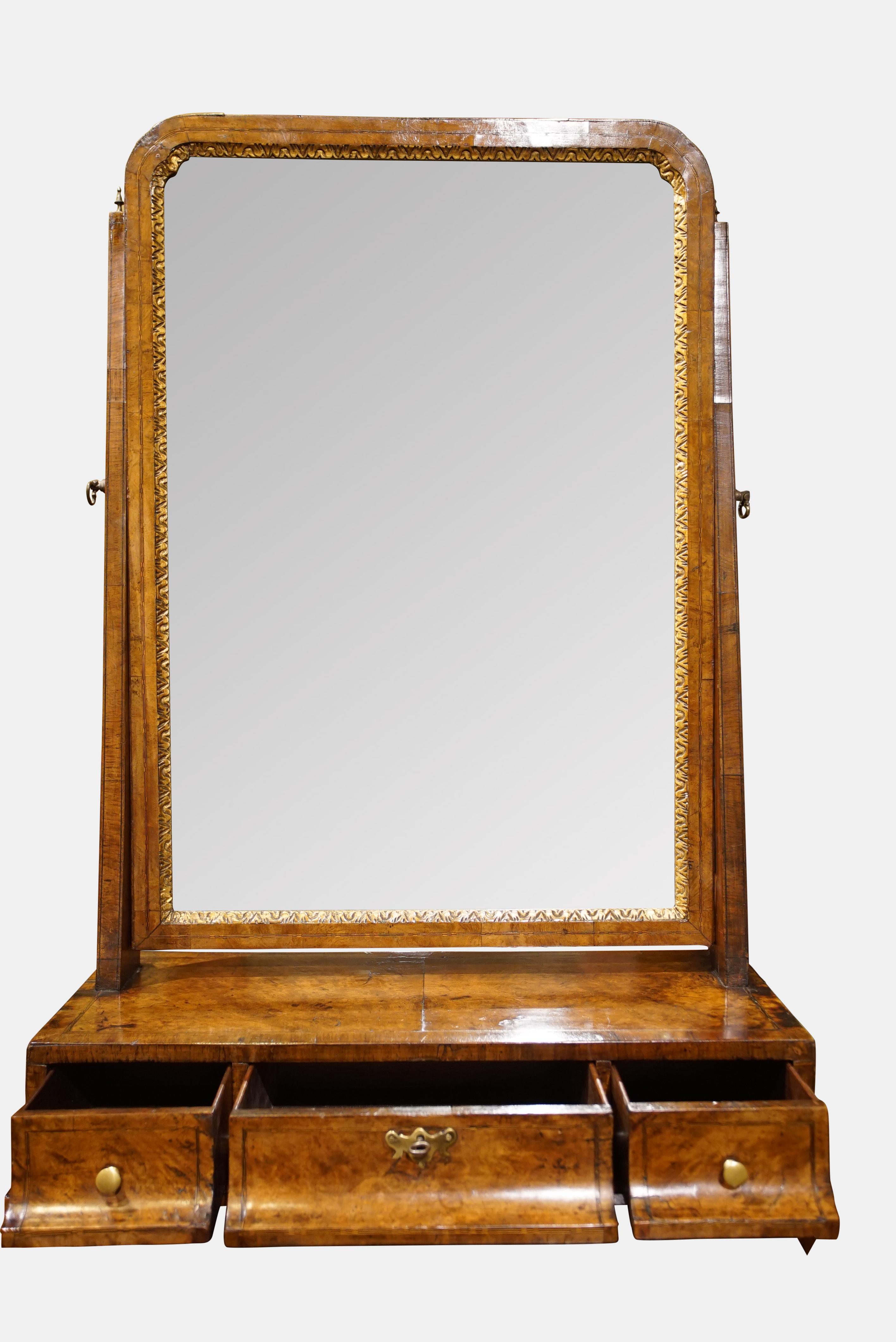 A George II walnut boxbase toilet mirror of large size, veneered in burr walnut, with three drawers below the mirror plate with carved gilt slip, all inlaid fine chequer lines. (Feet Restored)




circa 1740.