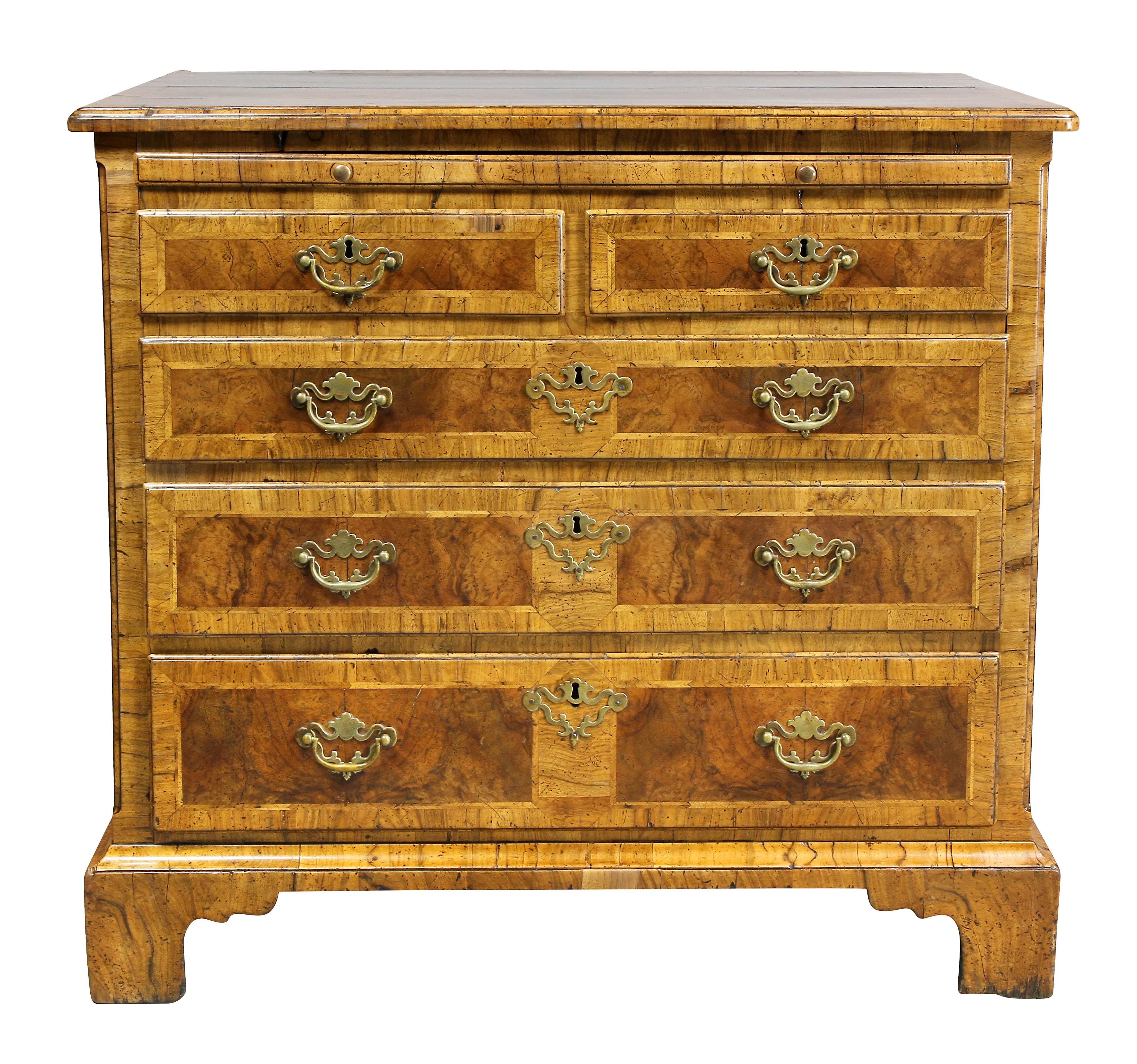With a cross banded burl walnut rectangular top over a brushing slide and four paneled graduated drawers, bracket feet.