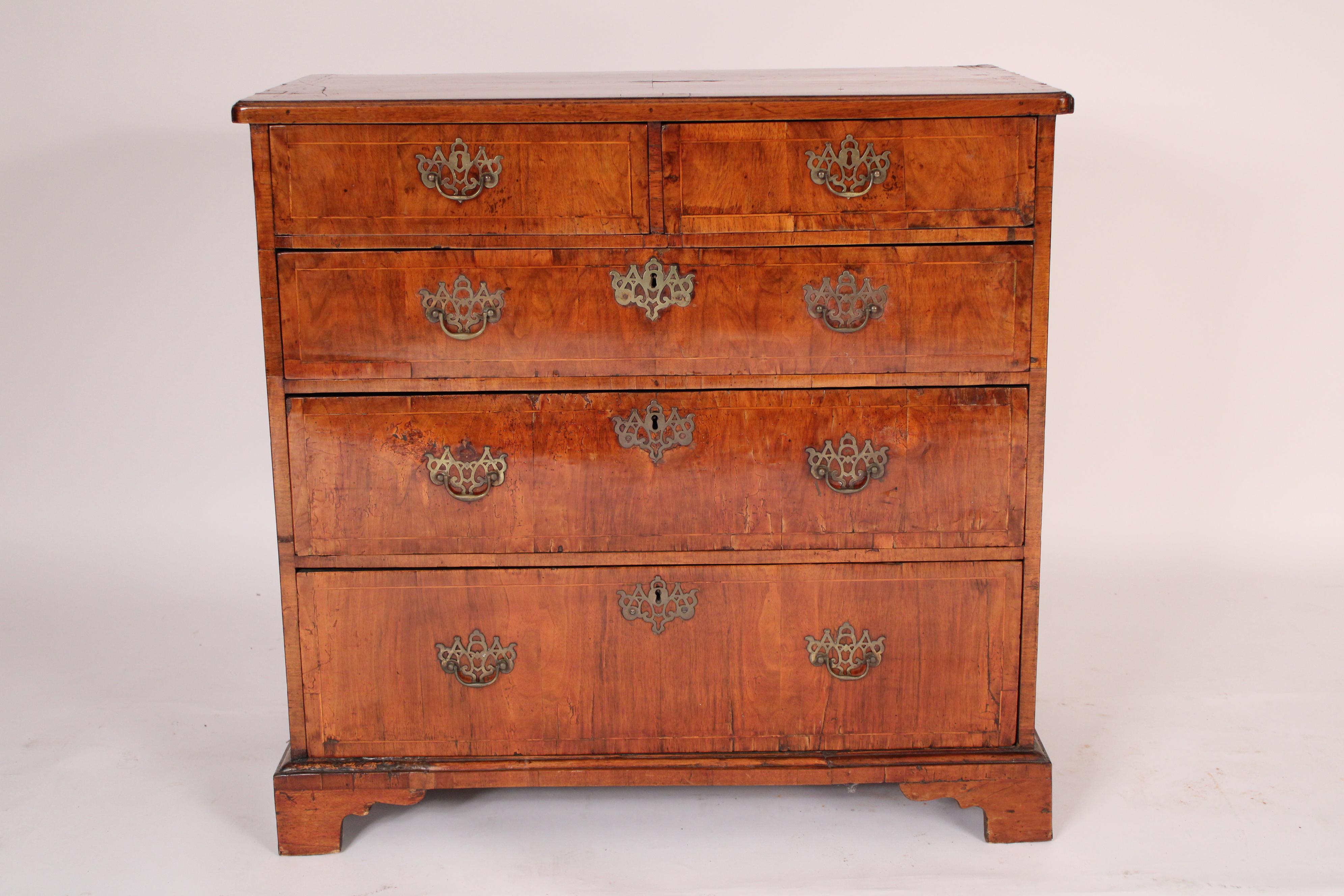 George II walnut chest of drawers, 18th century. With an overhanging rectangular top with two bands of string inlay, two top drawers and 3 graduated lower drawers all with string inlay, resting on bracket feet. 