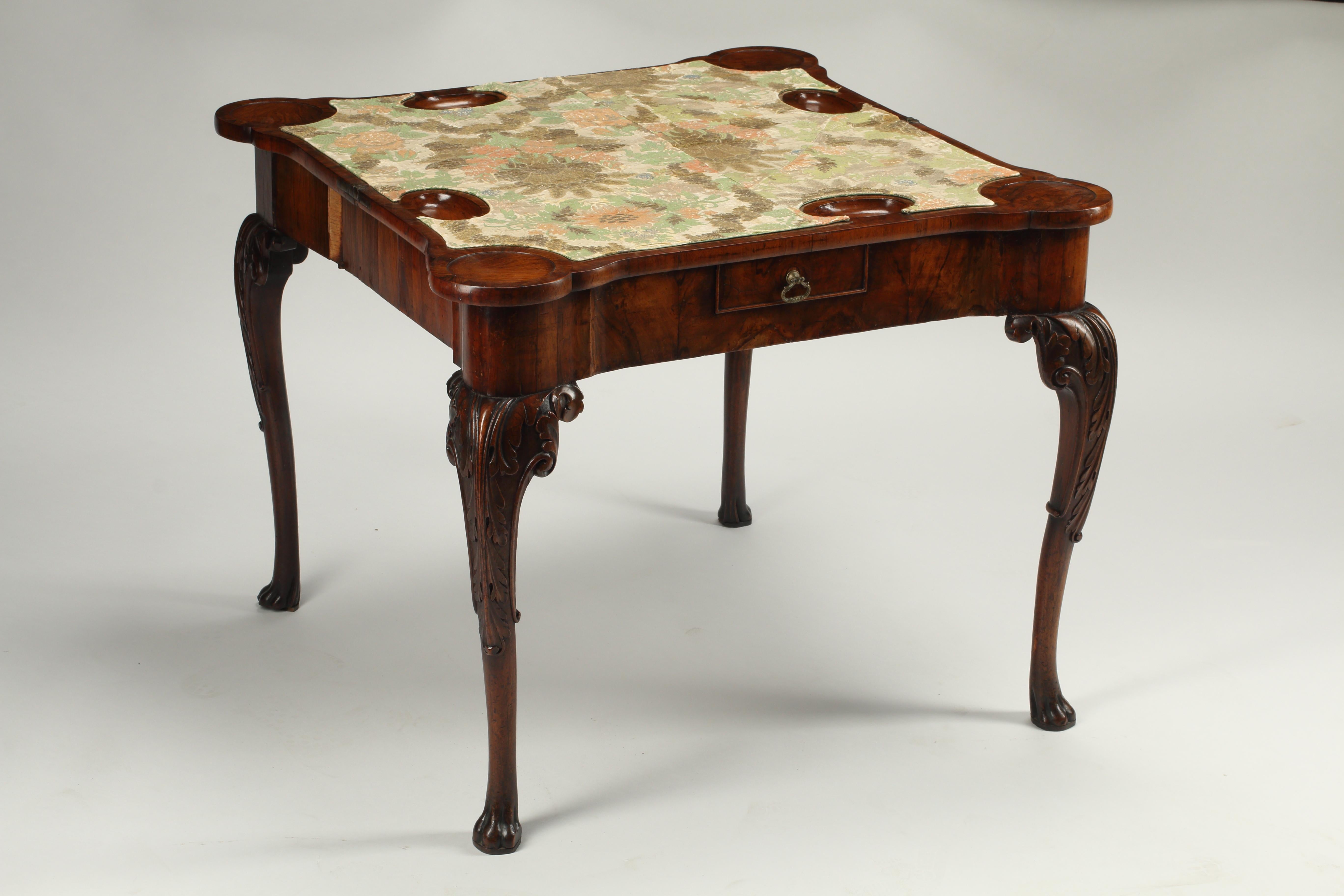This Irish George II/III carved walnut concertina action fold over games table is a fine example of Irish furniture from the mid-18th century. Made of solid walnut with a carved top and cabriole legs. The top folds down to reveal a floral print