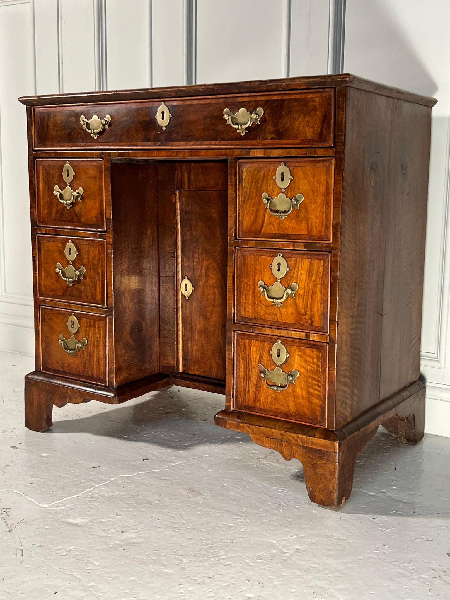 George II walnut knee hole desk.

Cross banded quartered top above an arrangement of drawers and a central cupboard raised on bracket feet.

Later handles and some repairs to veneers as pictured.

English circa 1760.

Measurements - 77cm h x