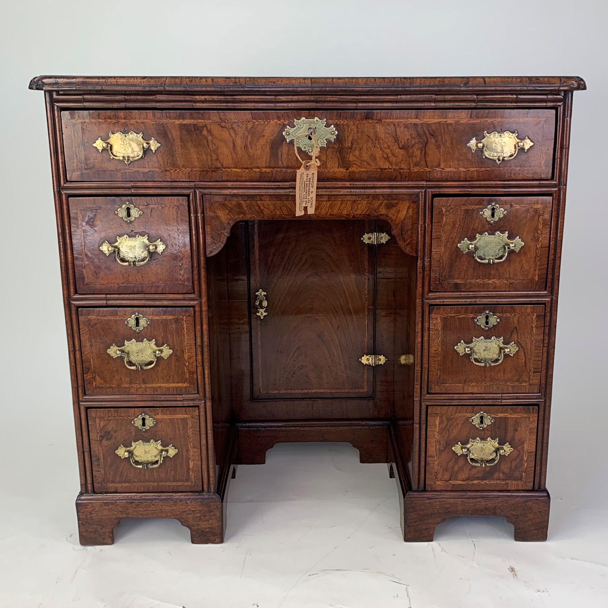 An especially fine quality George II period burr walnut kneehole desk with quartered 'bookmark-veneered' top with herringbone inlay and cross-banding, above a single long drawer and an arrangement of short drawers either side of a central recessed