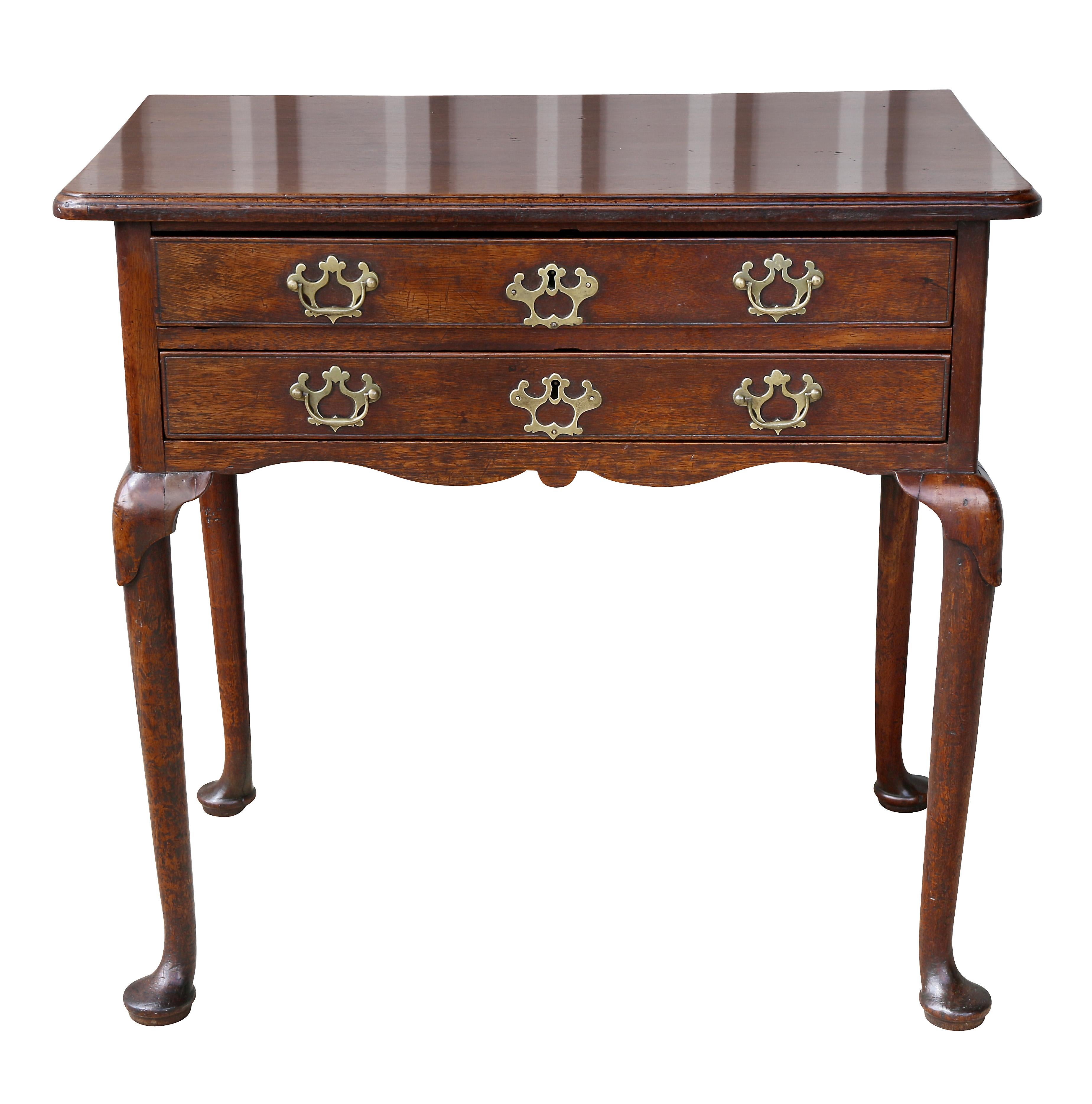 With a rectangular top over two long drawers with original handles, raised on cabriole legs and pad feet.