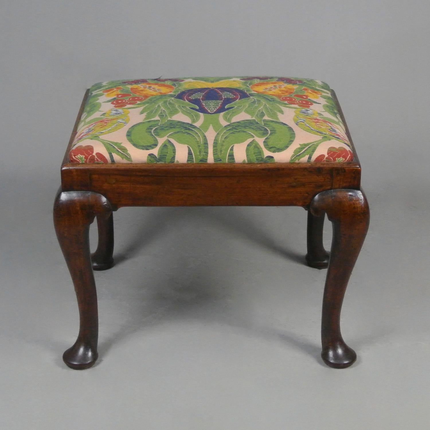 A lovely English stool made by hand in solid walnut and dating from c. 1740 and set on cabriole legs with button pad feet and well shaped hips.

Newly upholstered in a superb quality Gainsborough Silk Weaving Company tapestry fabric – a pattern and