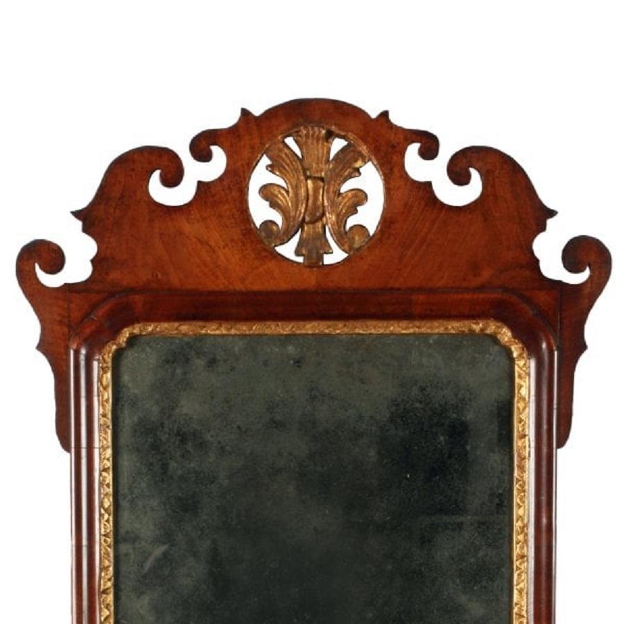 A mid 18th century George II walnut wall mirror.

The mirror is Chippendale in design with shaped decoration and a circular carved and gilded acanthus detail in the top centre.

The mirror has its original mirror plate that has a very slight
