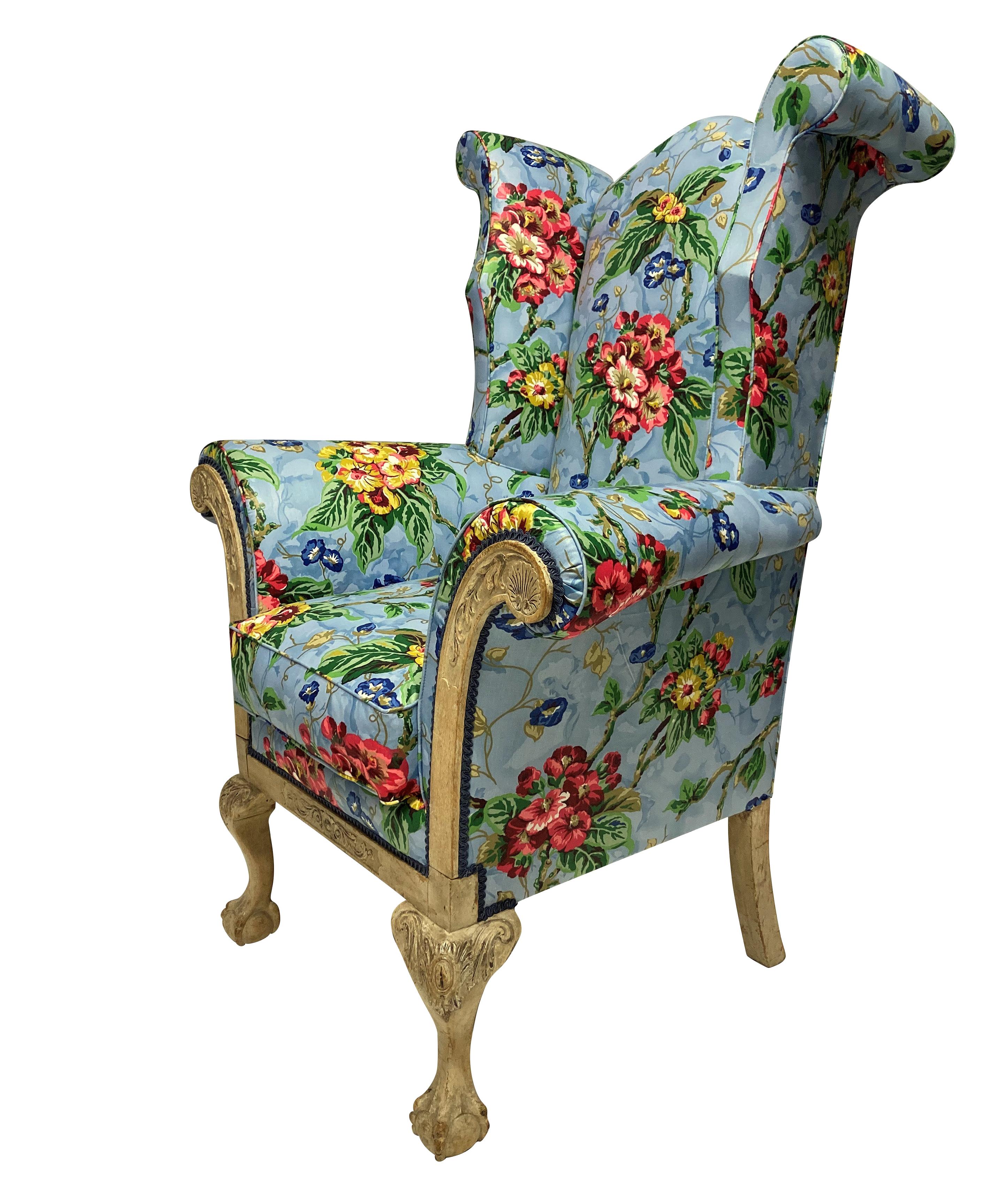 An English George II wing armchair of very generous proportions. The carved frame showing signs of early paint on fruit wood and walnut. Newly upholstered in vintage American glazed chintz.