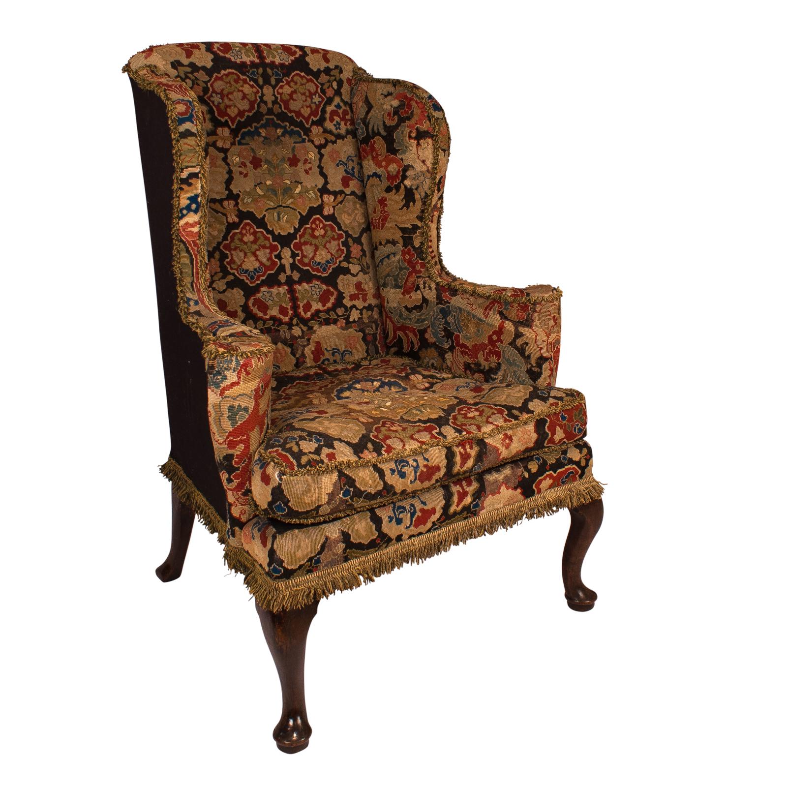 An English George II period wing chair upholstered in tapestry with mahogany legs, circa 1750.