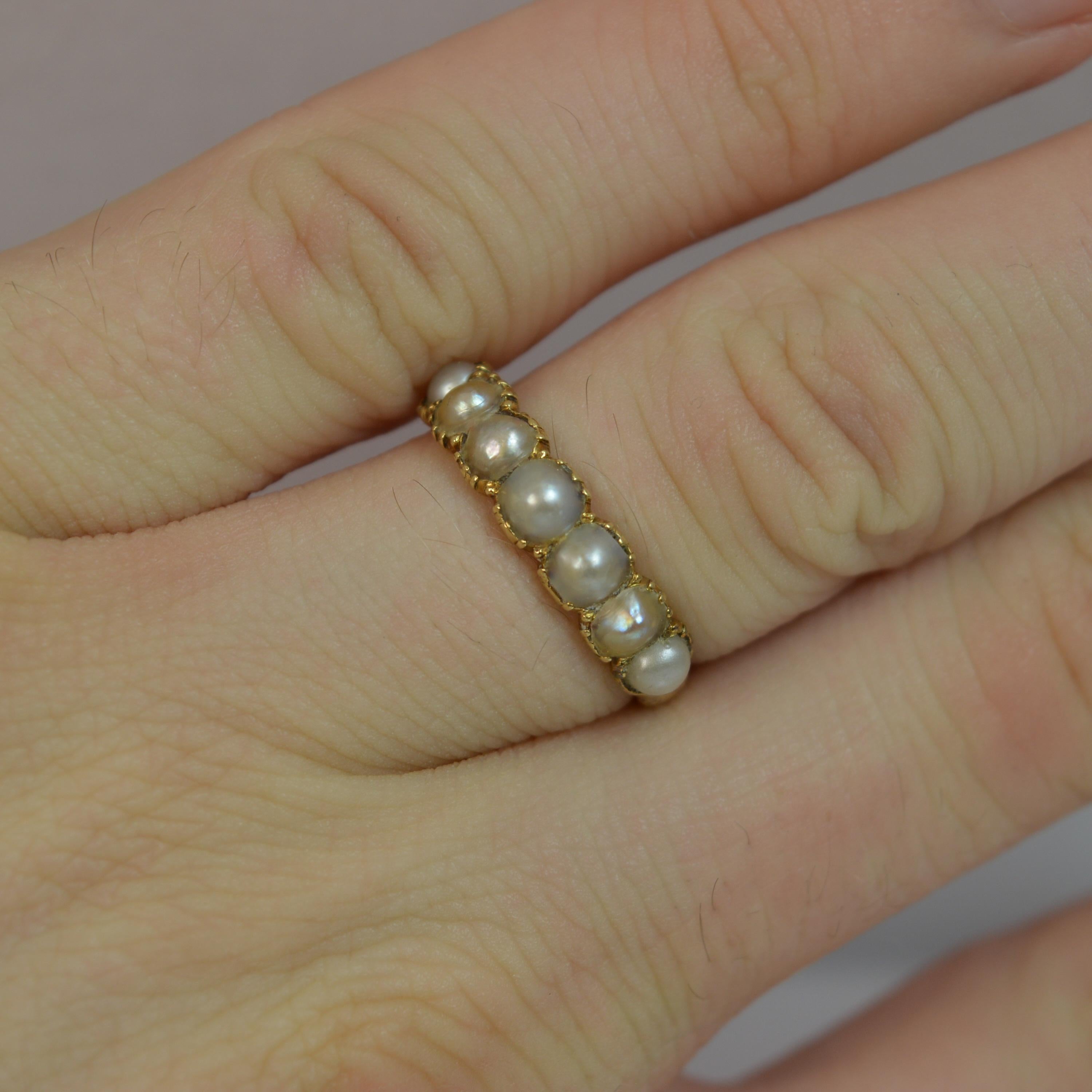 

A Georgian period ladies seven pearl ring. Solid 15ct gold shank. Stylish and elegant piece. Set with natural pearls to form a single row half eternity ring, ideal for stacking. 120m spread of stones, 4.5mm thick band to the front. c1770's. Fine