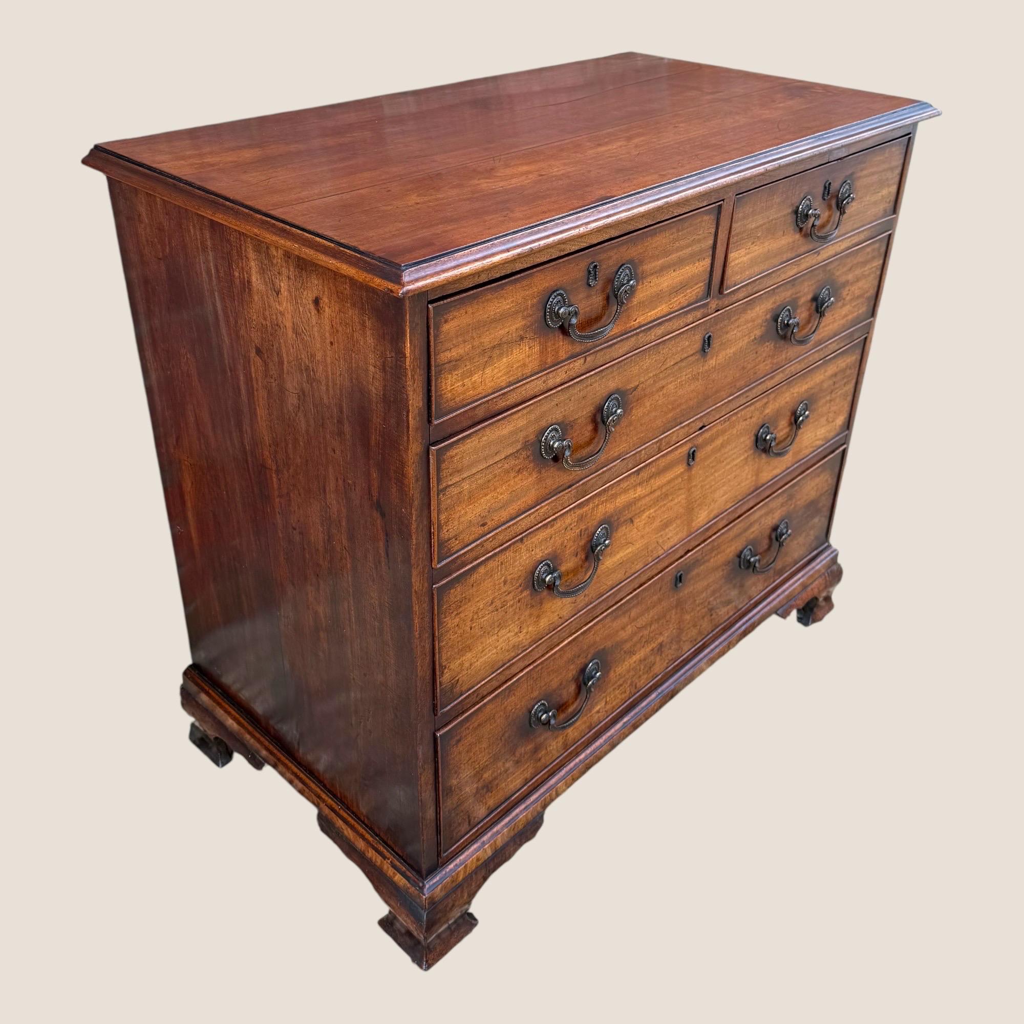 Aquí tenemos una cómoda de 5 cajones con tiradores de caoba y latón de pequeñas proporciones de Jorge III, hacia 1790, con patas conopiales del ebanista J Moorcroft. Con todas las empuñaduras, inscripciones de llaves y cerraduras originales de