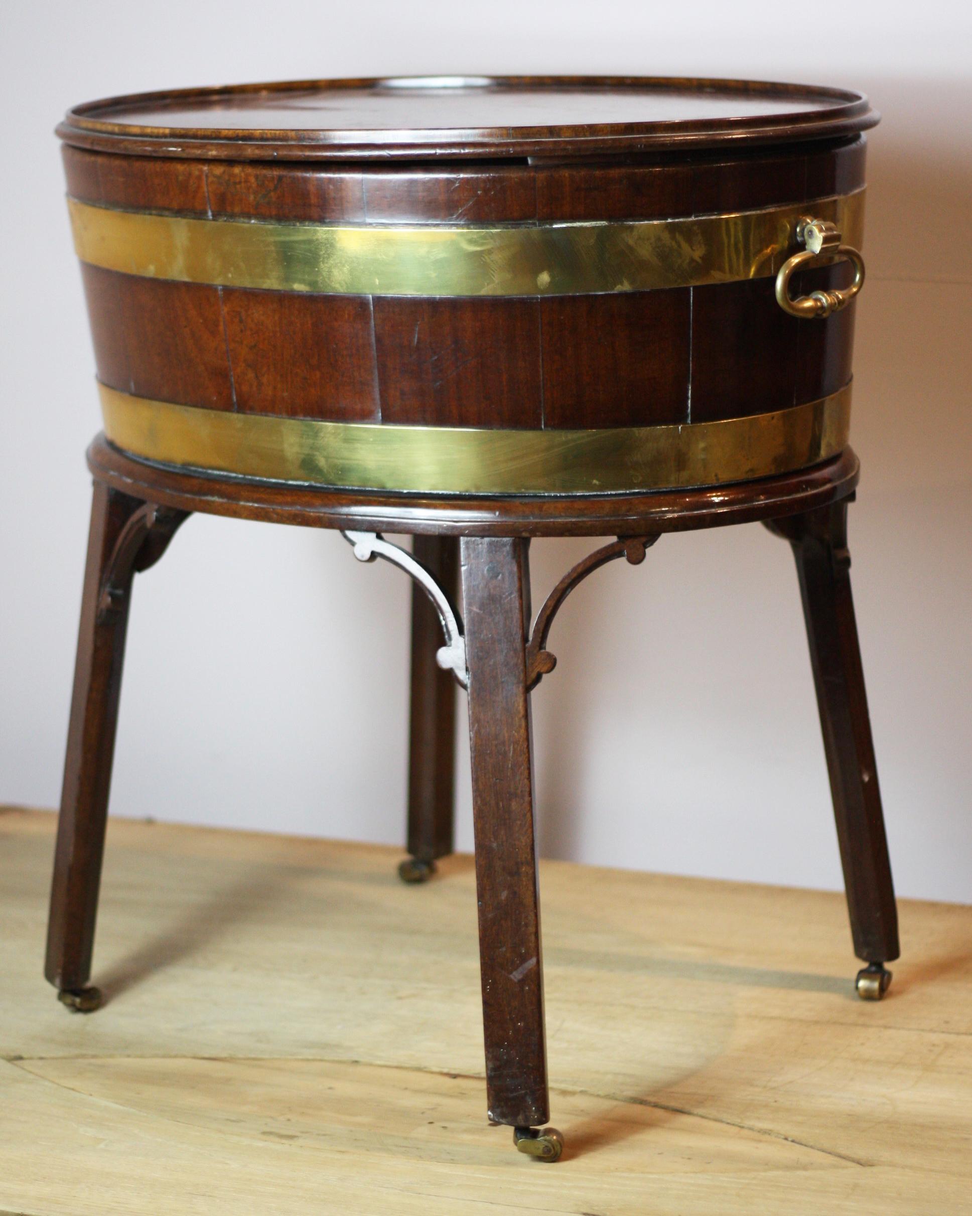A fine George III mahogany oval shaped wine cooler, with brass bands and carrying handles, on mahogany stand with small casters, also comes with later lid for use as a side table or would also make a wonderful planter, circa 1790.