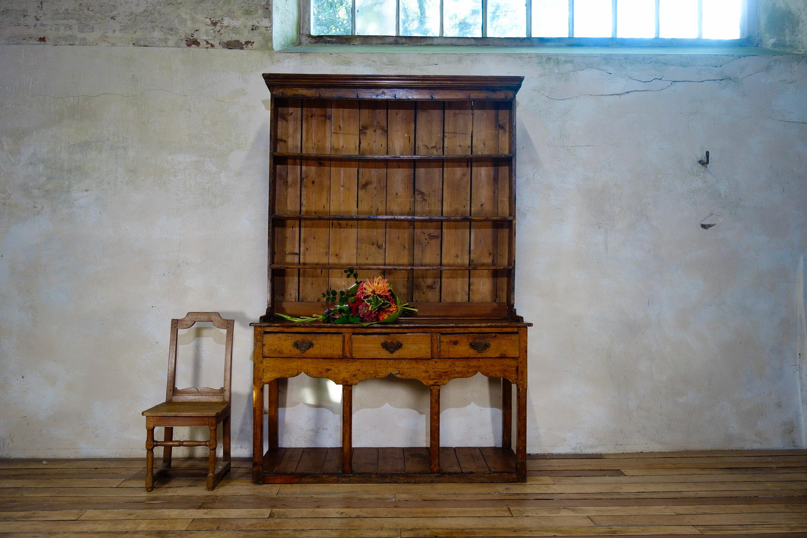A charming mid-18th century fruitwood and pine pot board cupboard.
Displaying a moulded top above three open shelves fitted with iron hooks to the top frieze rail and applied edge moulding.
The base houses three lip moulded frieze drawers and a