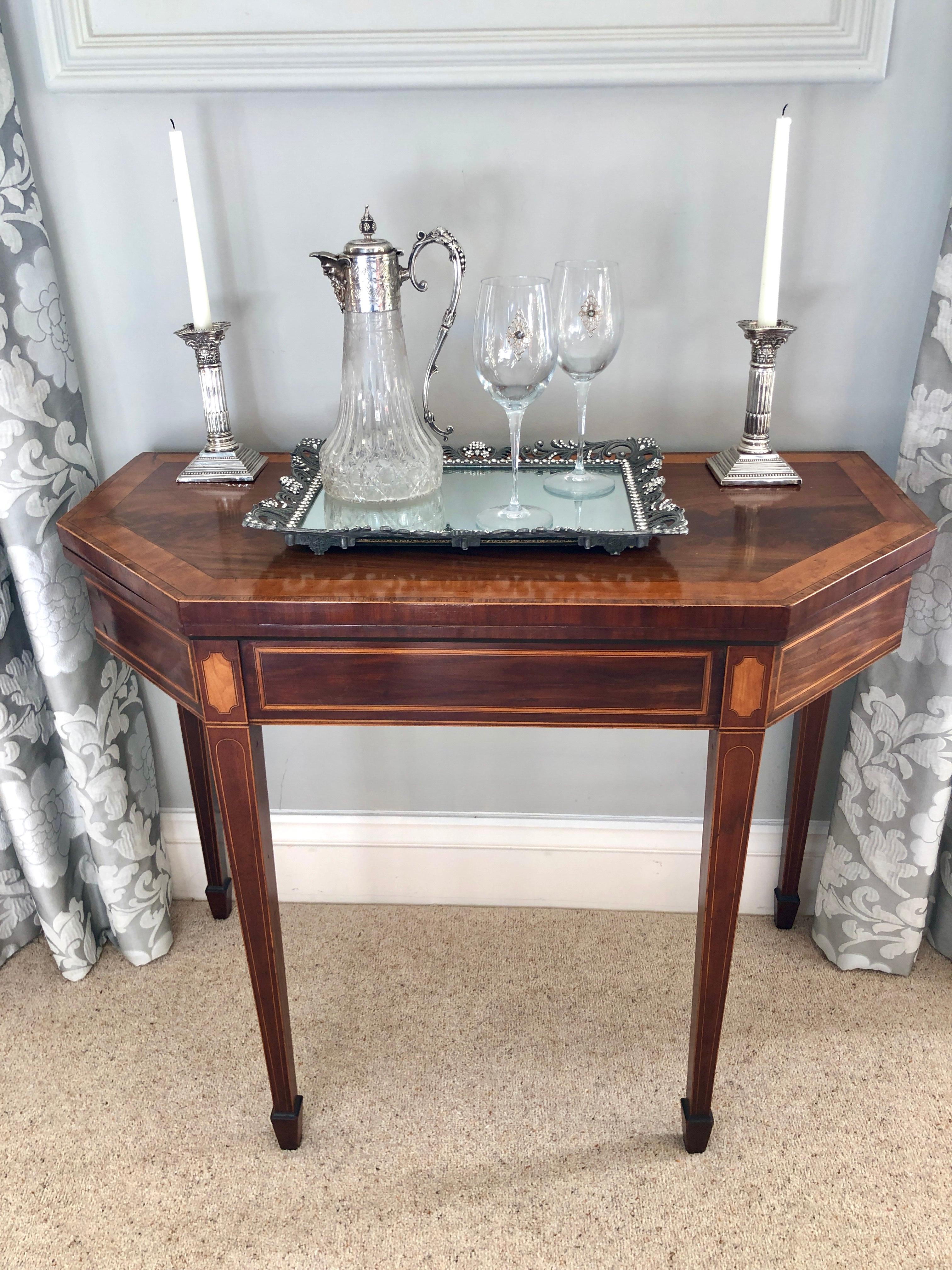 George III mahogany, satinwood and tulipwood banded fold over card table of attractive canted rectangular form having a wonderful patina with hinged leaf enclosing a green baize lined interior. It is raised on elegant square inlaid legs with spade