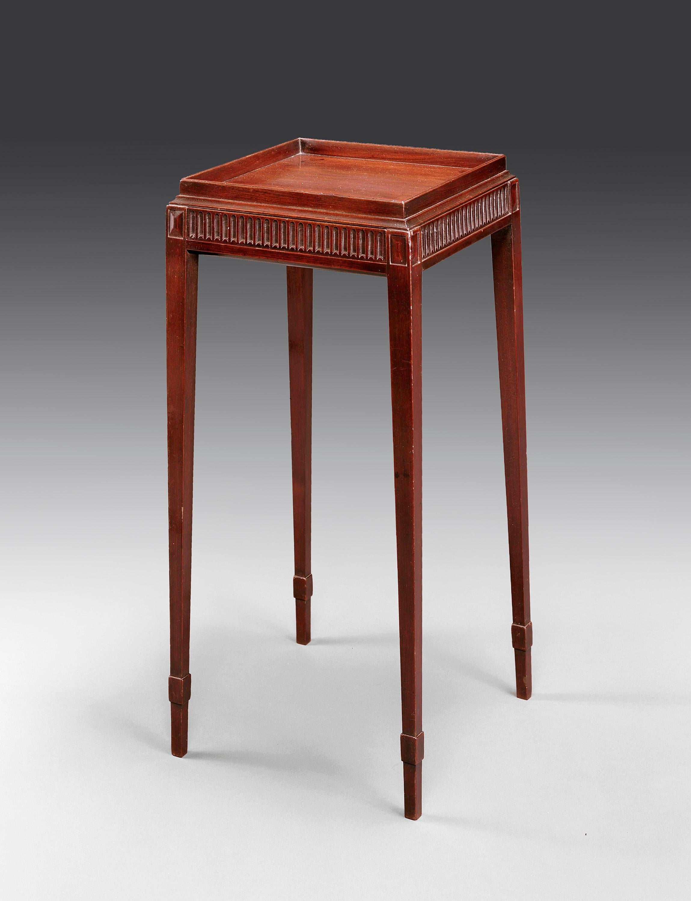 The stand has a raised gallery around a well figured square top above a fluted frieze with a single drawer to the front. The table is supported of four square tapered legs with bandaged toes.