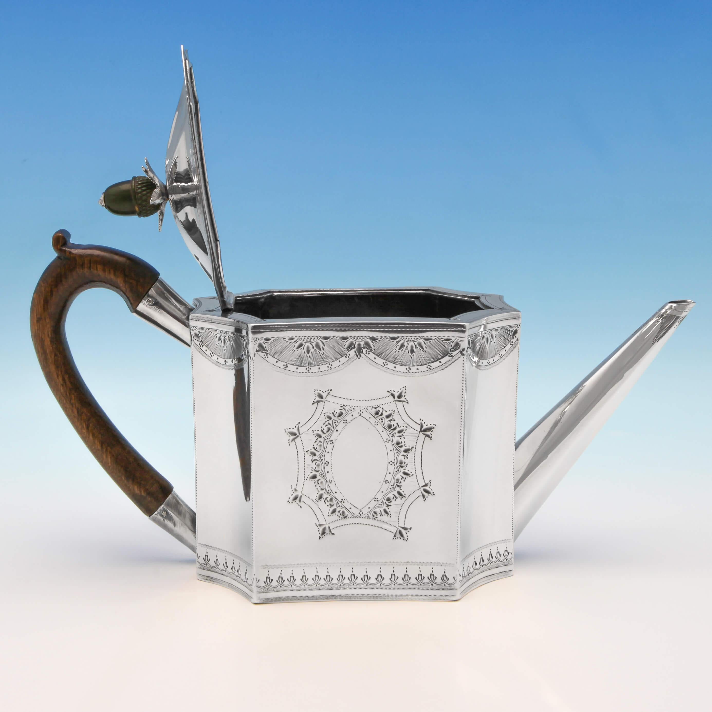 Hallmarked in London in 1790 by Charles Hougham, this exceptional, George III, antique sterling silver teapot, has an unusual shape and wonderful bright cut engraved decoration throughout, with a fruitwood handle and an ivory acorn shaped finial.