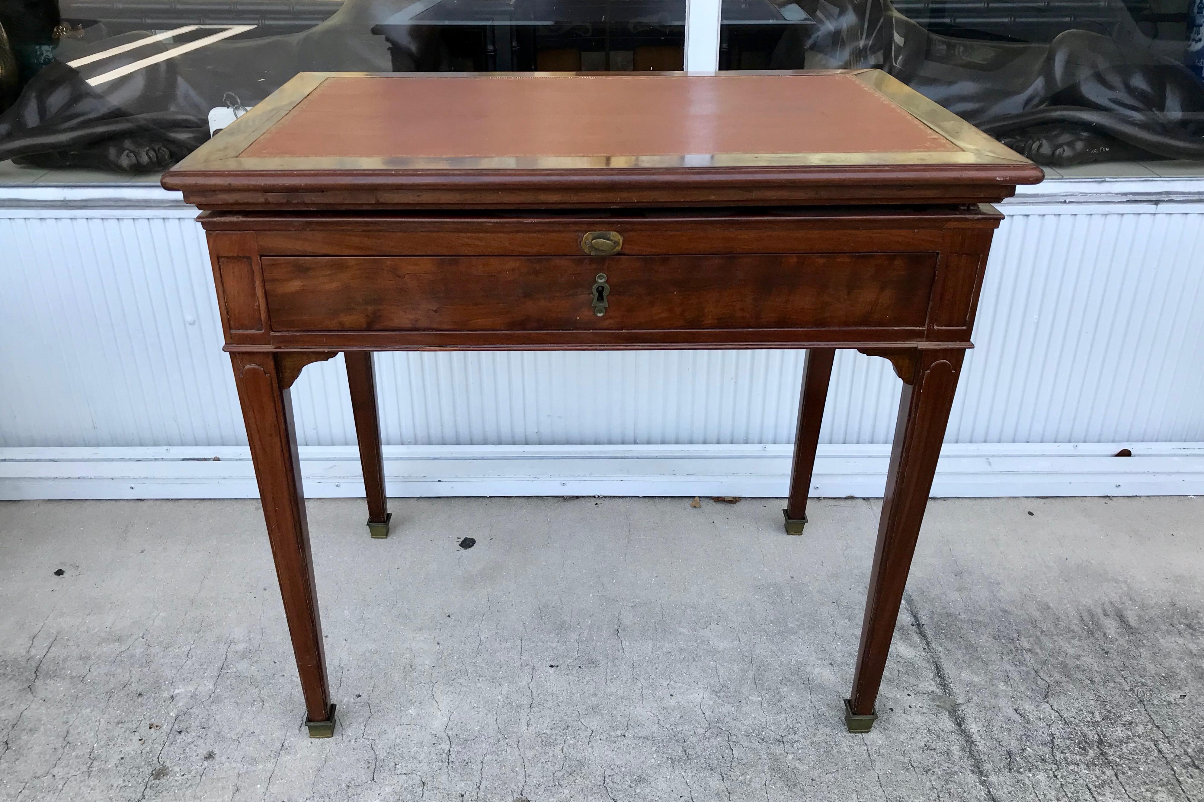Rich mahogany, appointed with a gilt tooled leather inset top.
The top is hinged and fitted with a slide for the adjustable top.
The piece is fitted with a single drawer.
The desk has been measured when closed.