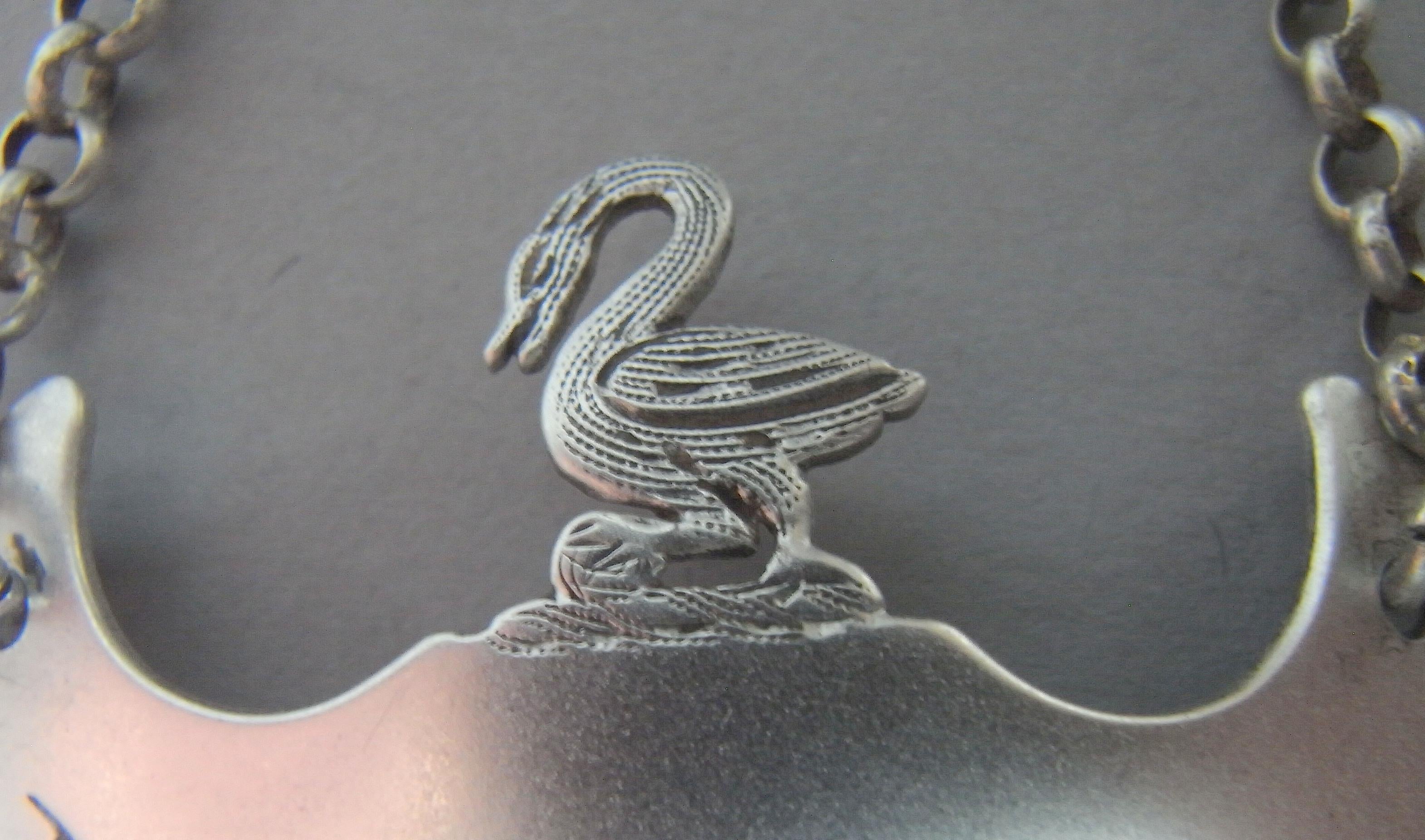 An Extremely Rare George III Armorial Wine Label Made in Newcastle circa 1805 by Ann Robertson.

This very rare Armorial wine label is modelled in the stylised crescent form. Most unusually, however, is that the top displays a contemporary cast Swan