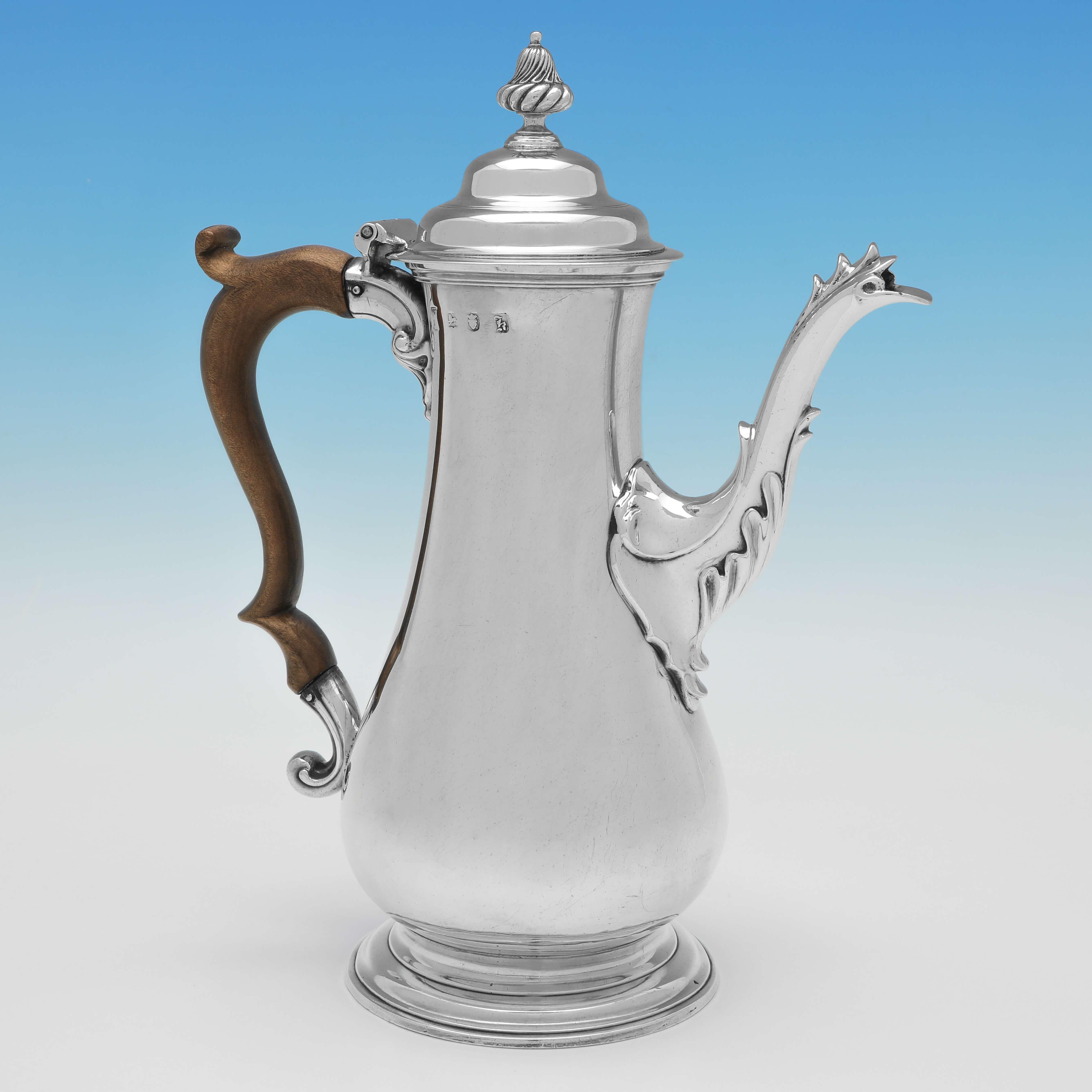 Hallmarked in London in 1765 by William & James Priest, this handsome, George III, Antique Sterling Silver Coffee Pot, has a plain body and lid, a wooden scroll handle, and acanthus detailing to the spout. 

The coffee pot measures 10.5