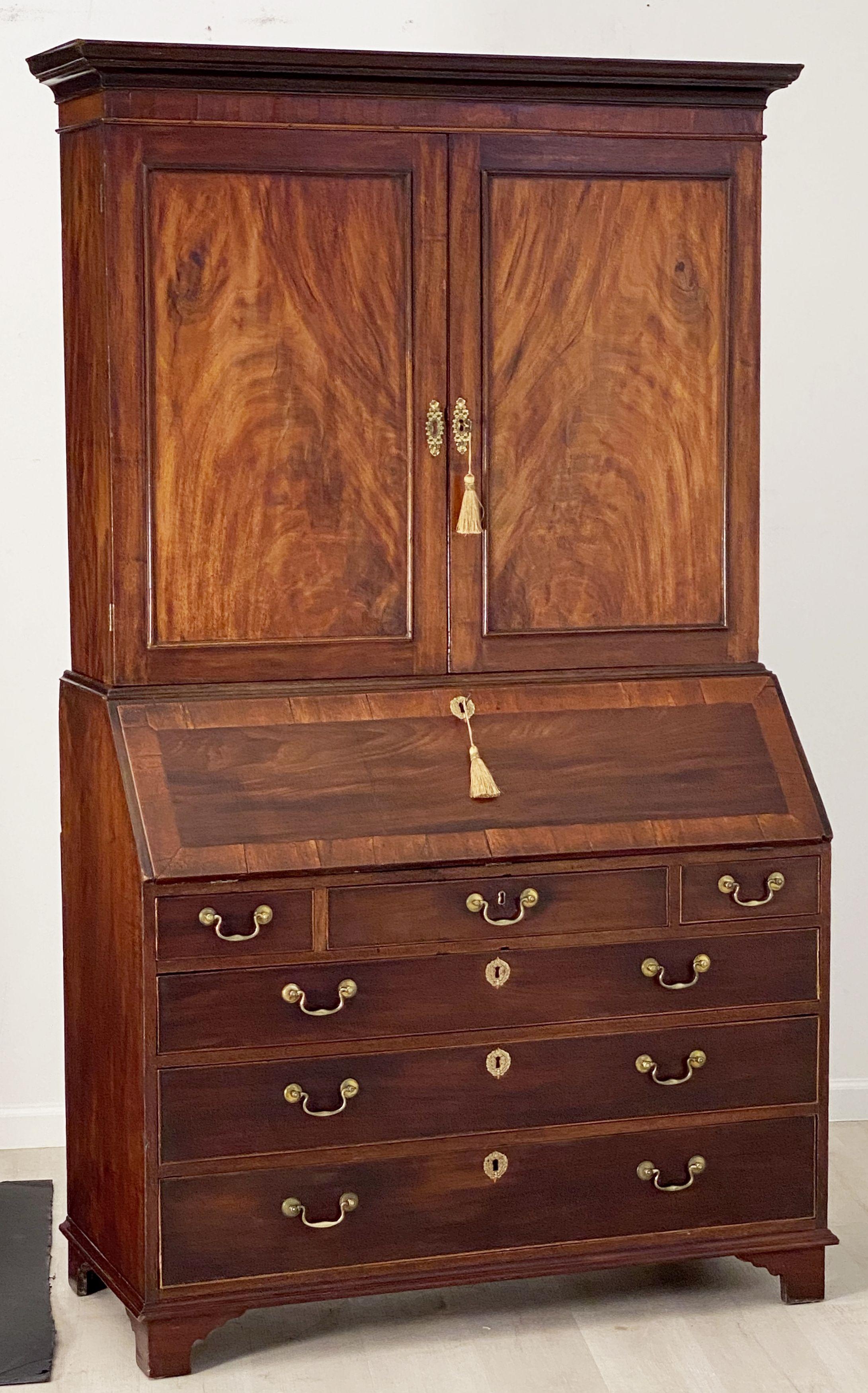 A handsome English bureau bookcase or secretary from the George III period, featuring a canopy top over two paneled doors of flame-cut mahogany, opening to a a bookcase with fitted shelves, set upon a slant top bureau desk base, the fall opening to