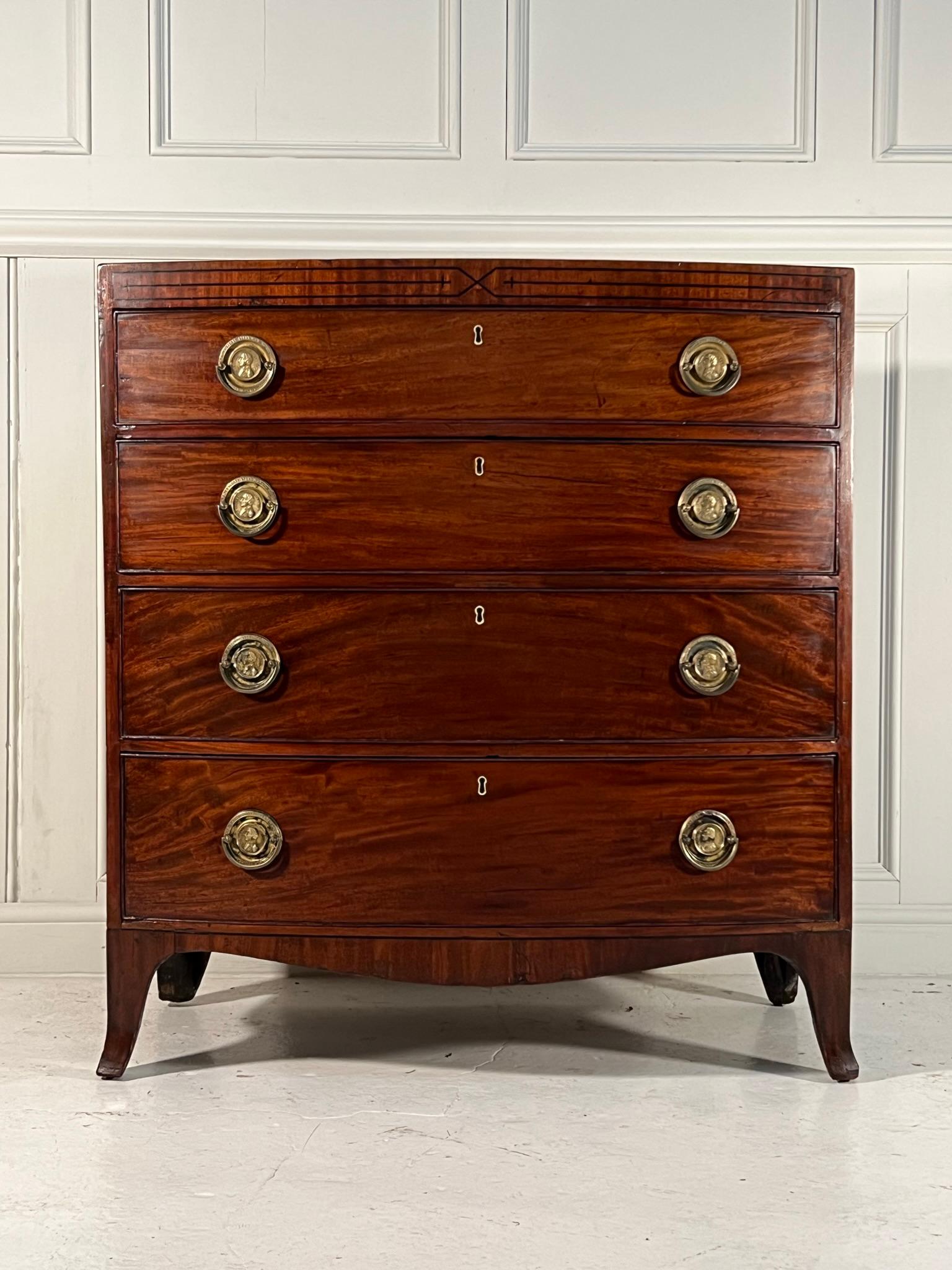 George III bow fronted, caddy top chest of drawers.

Figured Mahogany, caddy top and apron adorned with ebony stringing, raised on splay legs.

The brass work depicts lord nelson and his quote “England expects every man to do his duty”.

This