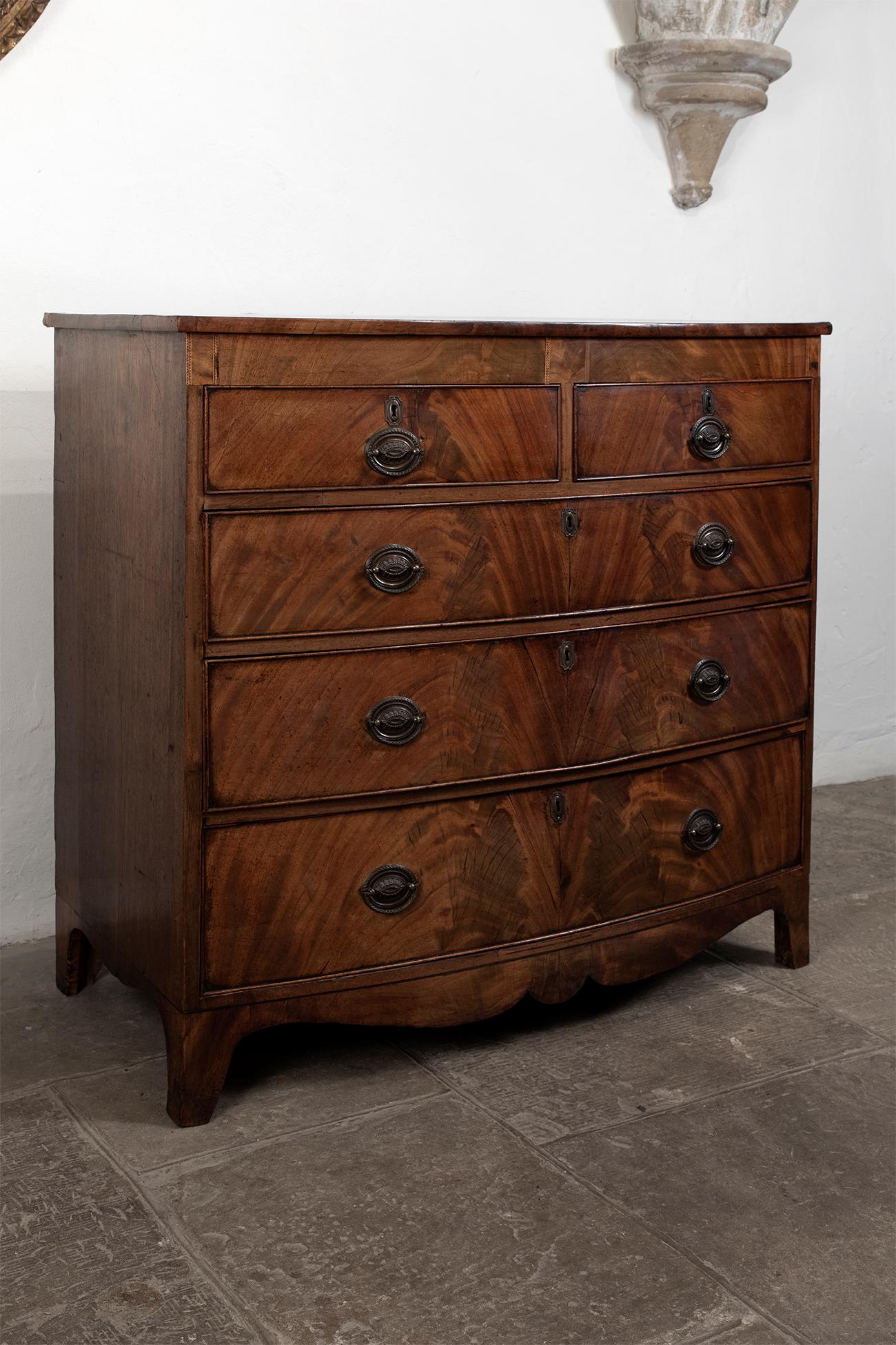 A rather handsome George III flame mahogany bow fronted chest with two short over three long drawers. Crossbanded top with detailed ebony stringing on feet. Fitted with original decorative brass handles. Overall condition is excellent, small area of